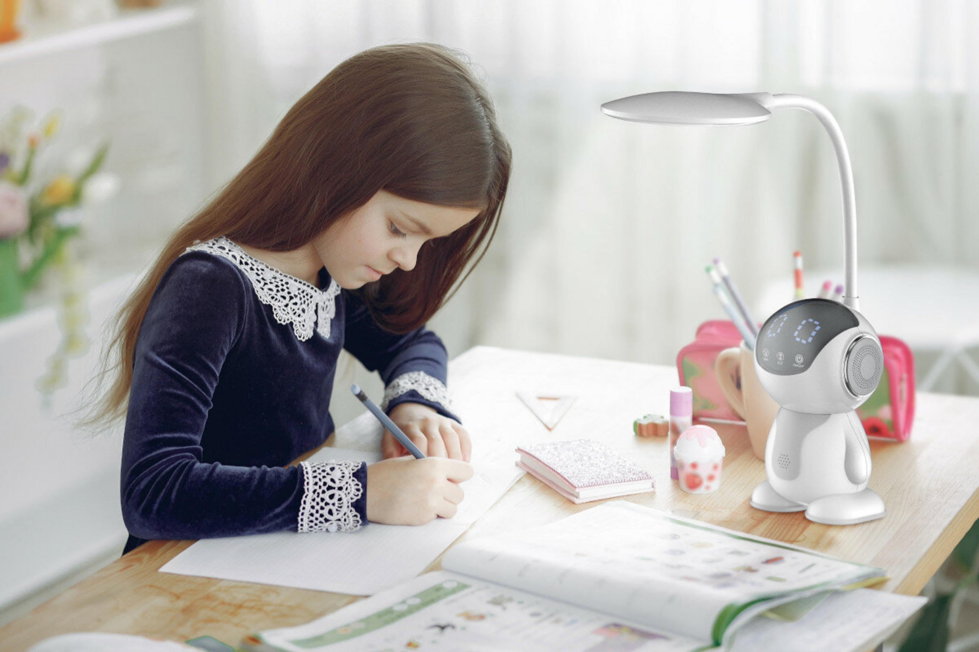 Una ragazza scrive a una scrivania con una lampada, un robot e un libro. Indossa un vestito blu con pizzo.