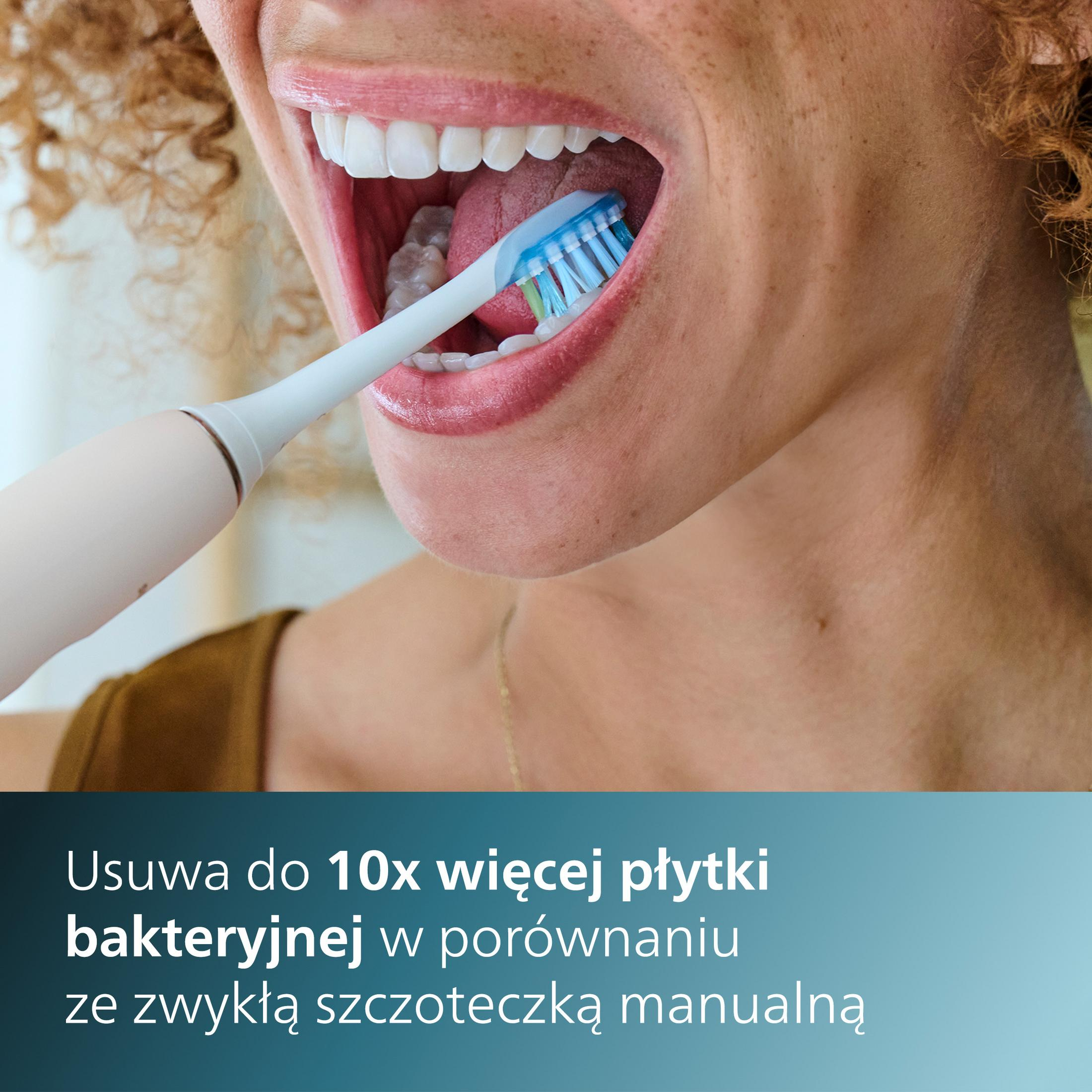 Close-up of a person brushing teeth with an electric toothbrush. Blue and white bristles are visible.