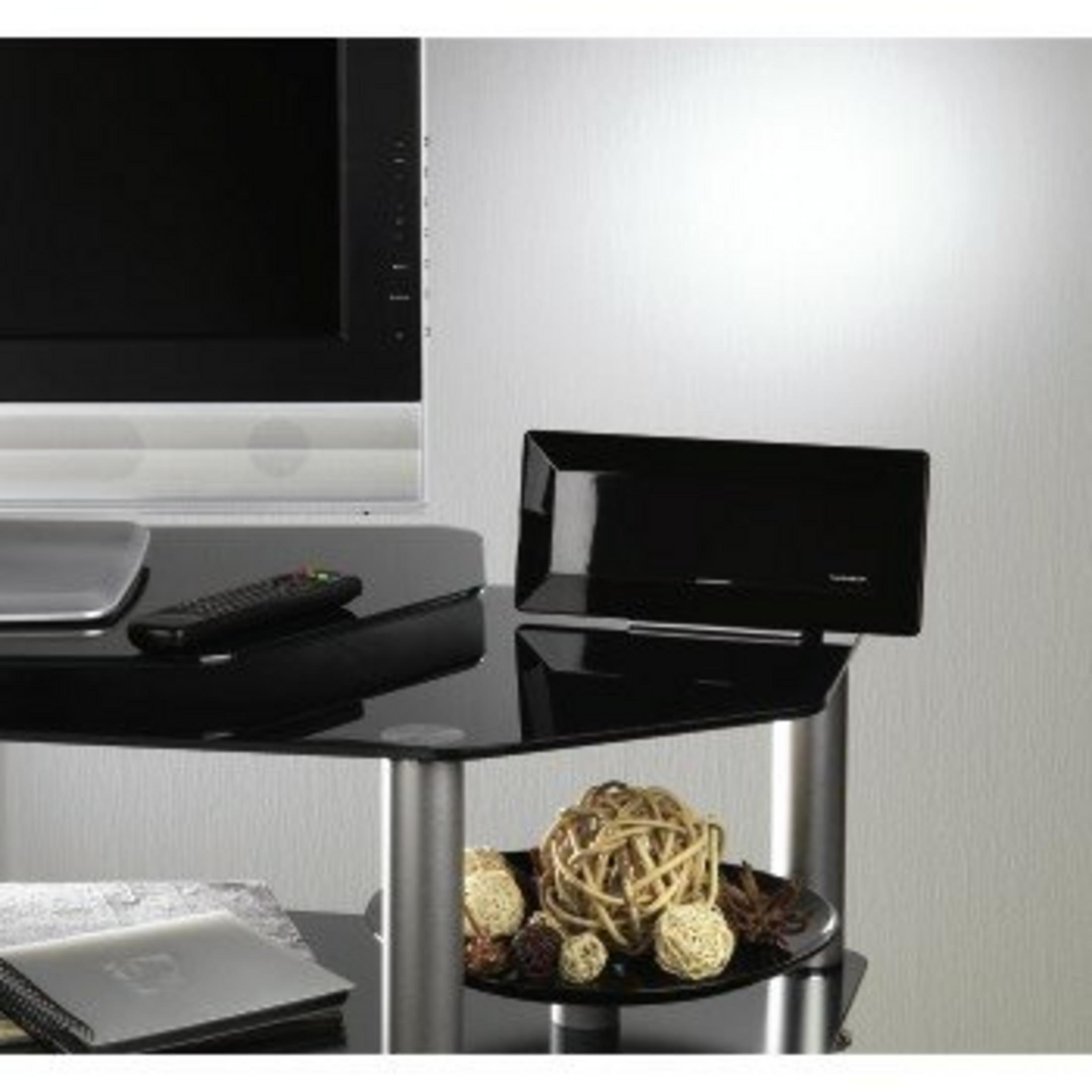 Nowoczesny czarny szklany stojak pod telewizor. Mieści telewizor, pilota i głośnik. Ozdoby to m.in. kulki.