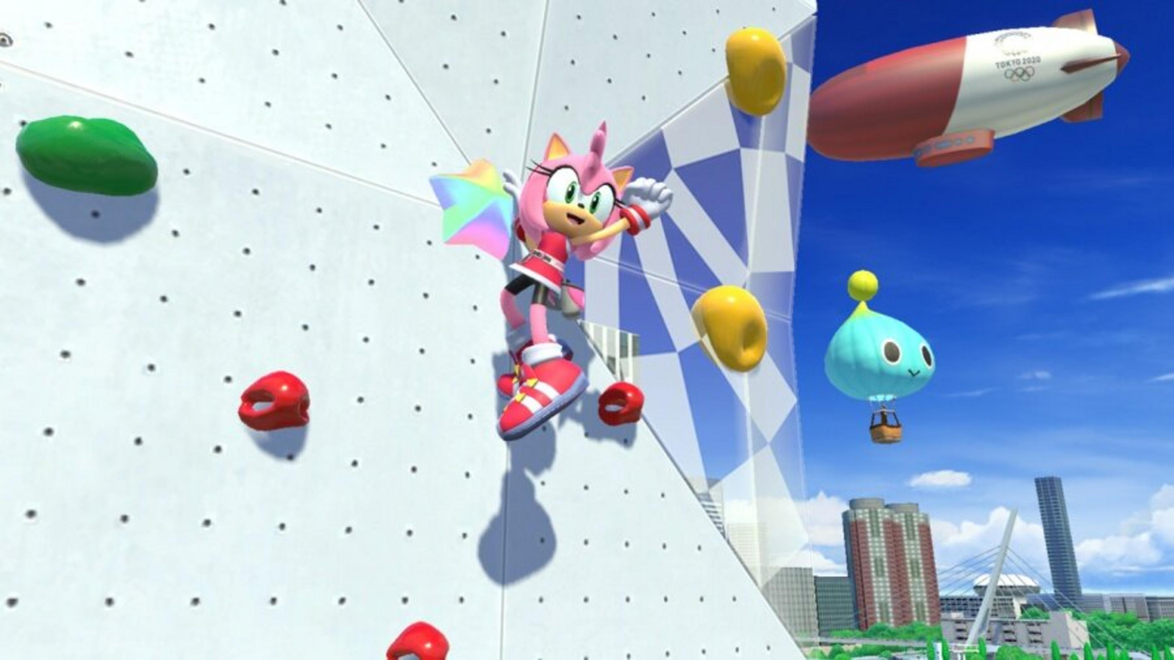 Amy Rose escala una pared con agarres. Un dirigible, Chao y una ciudad están en el fondo. El cielo es azul.