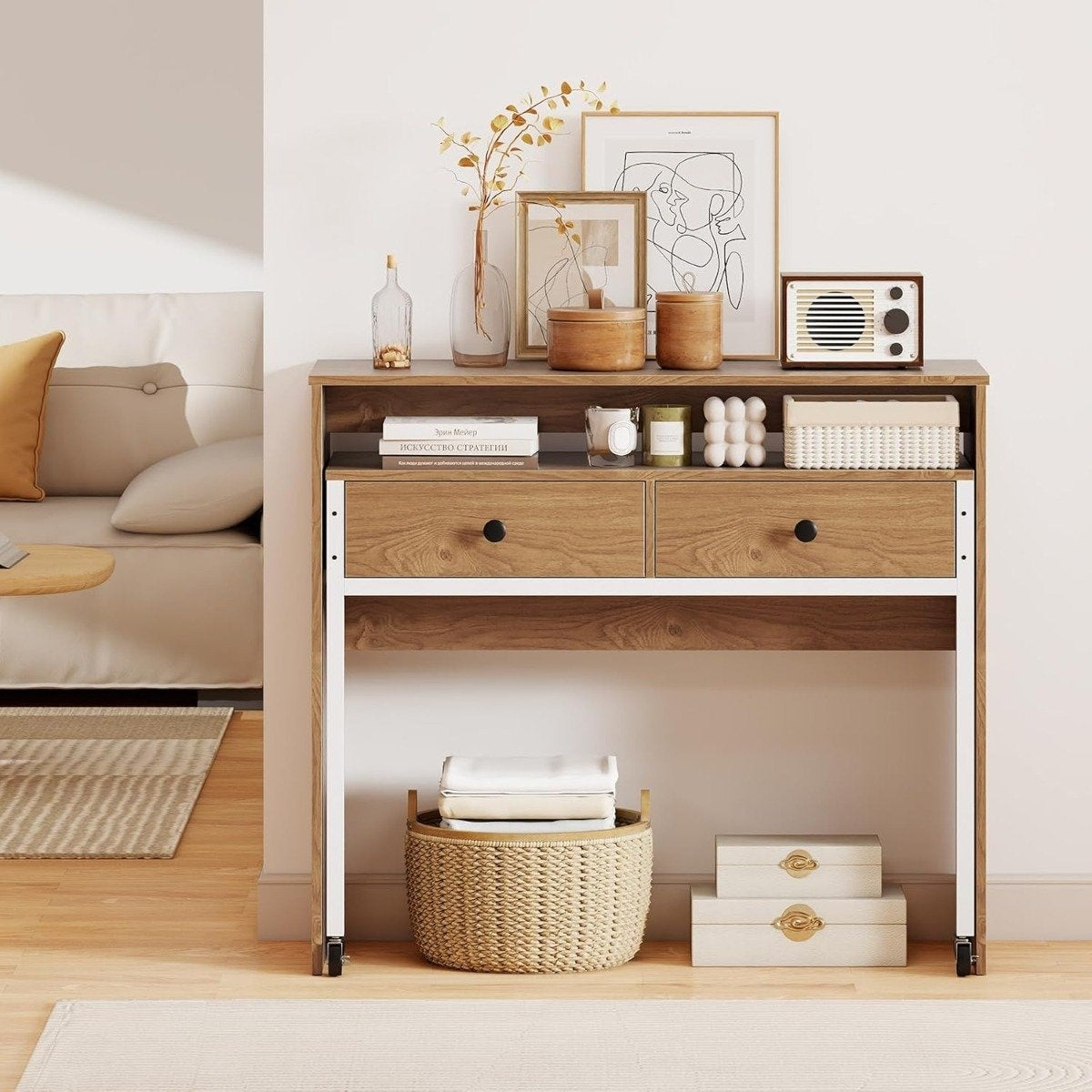 Una consola de madera con decoración, cajones y una cesta tejida. Un sofá y una alfombra son visibles en el fondo.