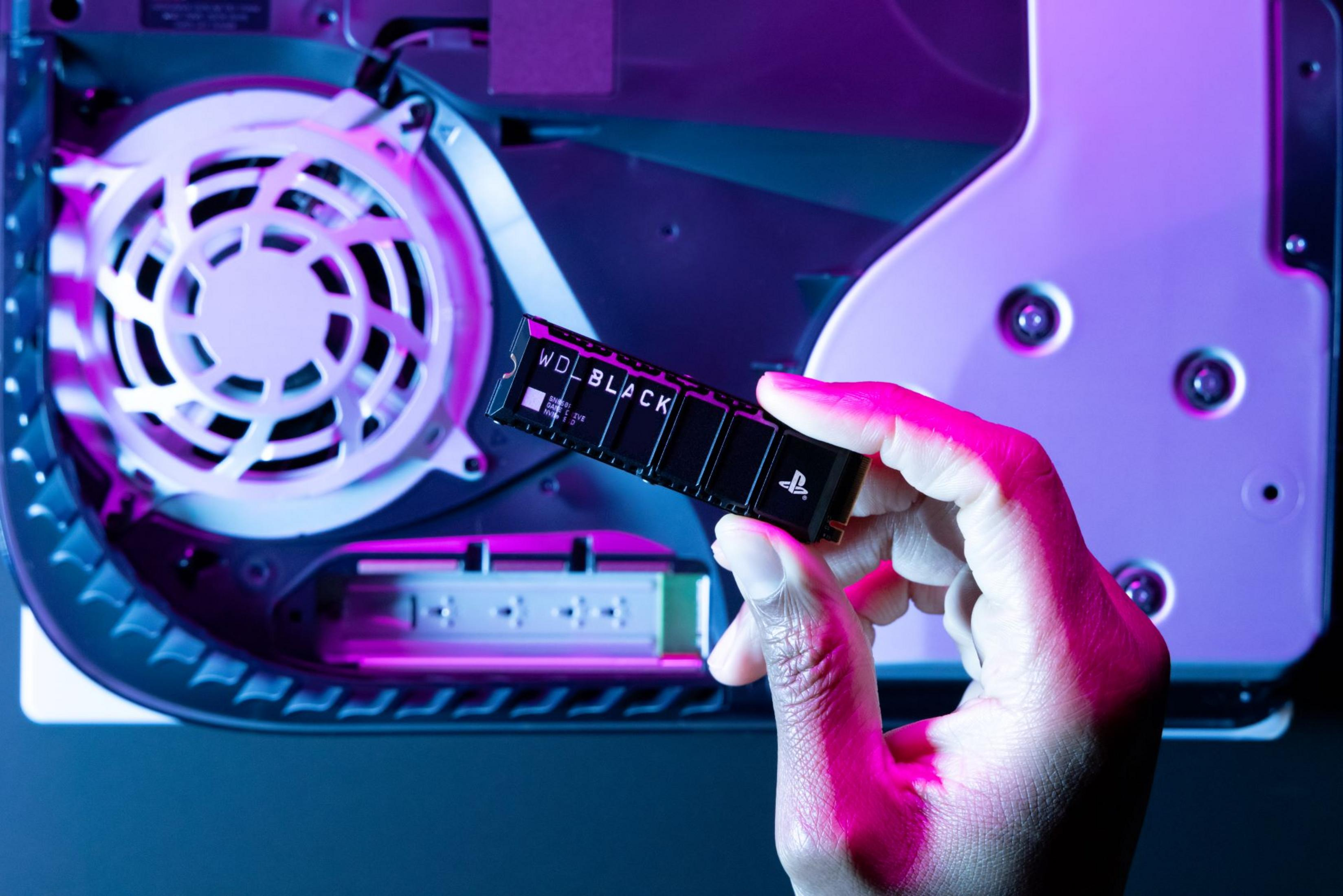 Dłoń trzymająca dysk SSD WD Black w PS5. Tło z wentylatorem i niebiesko-fioletowym oświetleniem.