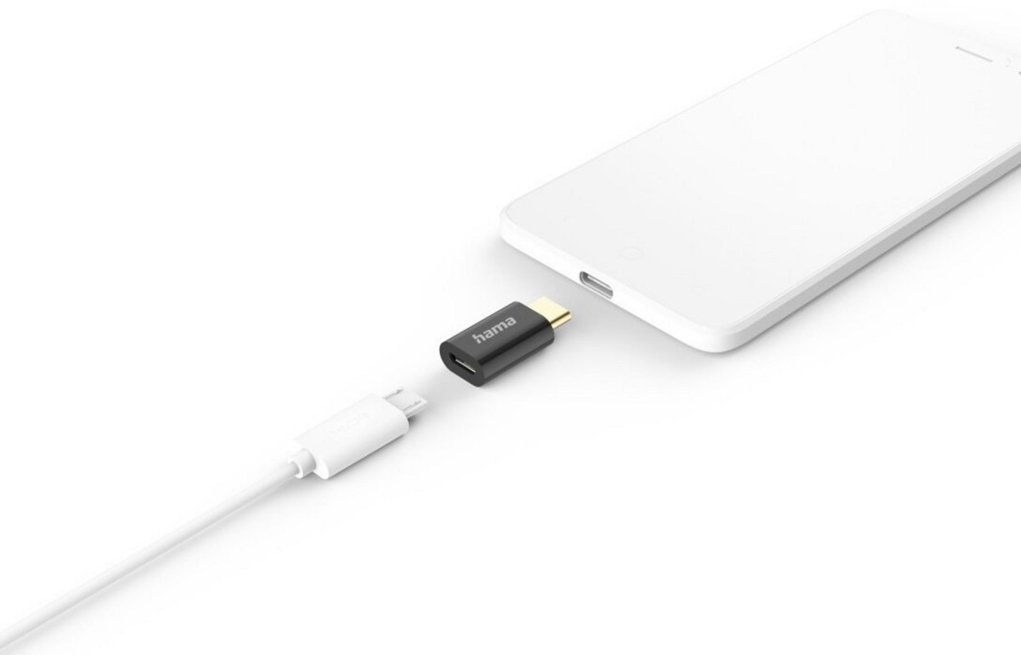 Biały telefon z czarnym adapterem obok białego kabla na białej powierzchni.