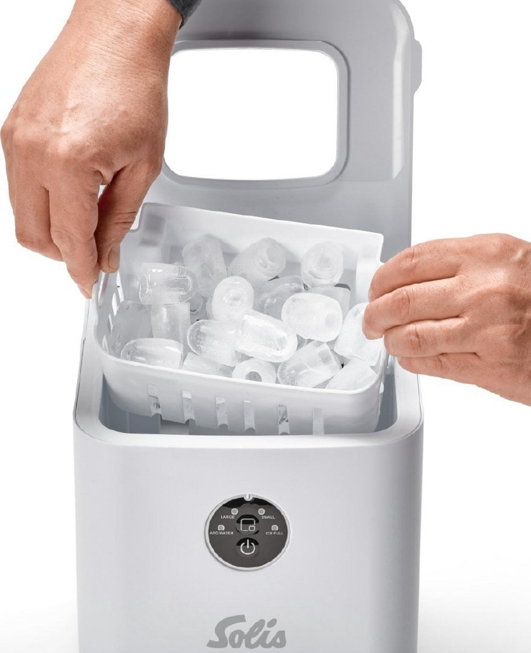 Hände entnehmen einen Korb mit Eiswürfeln aus einem weißen Eisbereiter. Der Eisbereiter hat ein Solis-Logo.