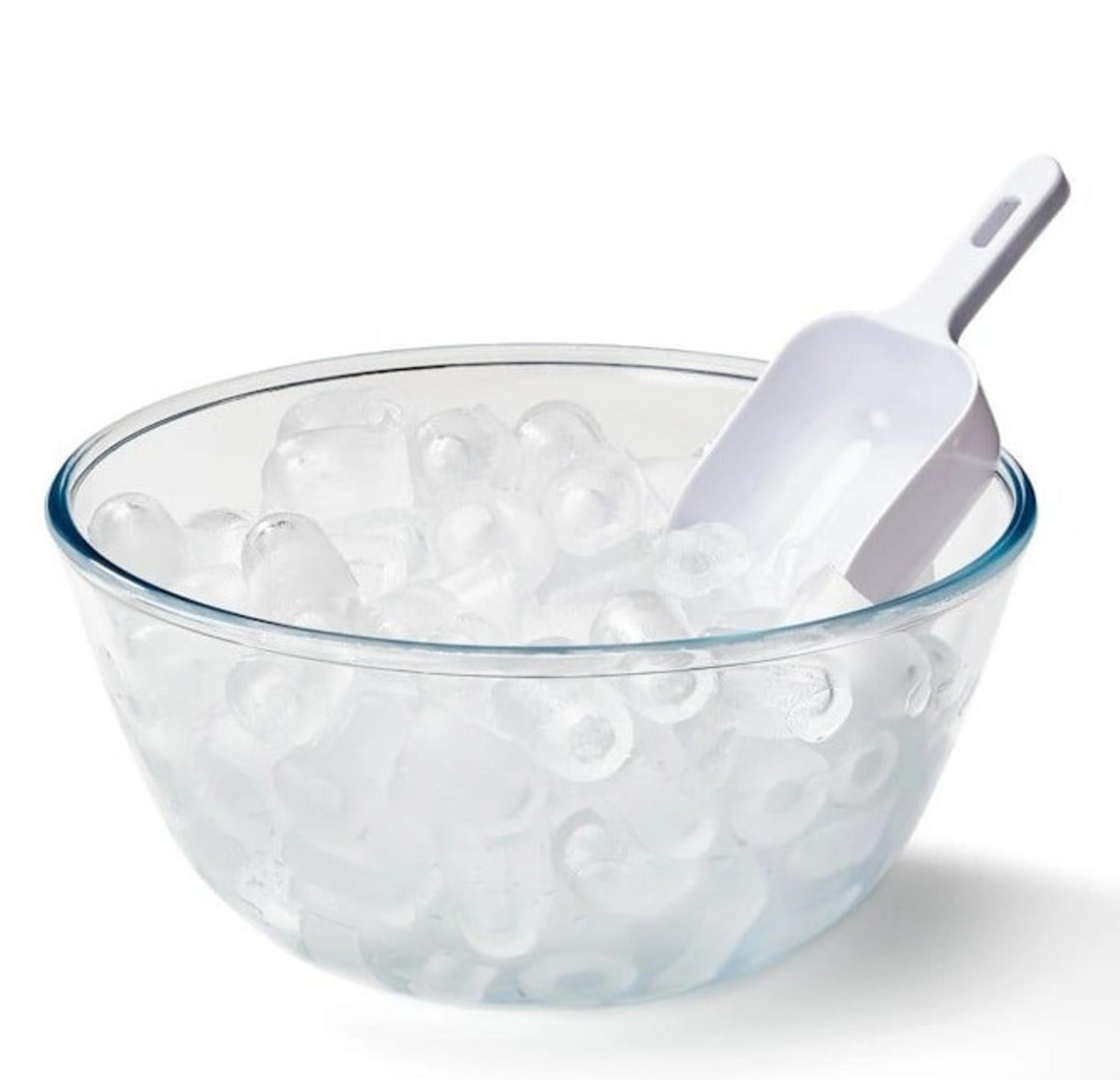 Eine klare Glasschüssel mit Eiswürfeln und einem weißen Eisschöpfer. Die Schüssel steht auf weißem Grund.