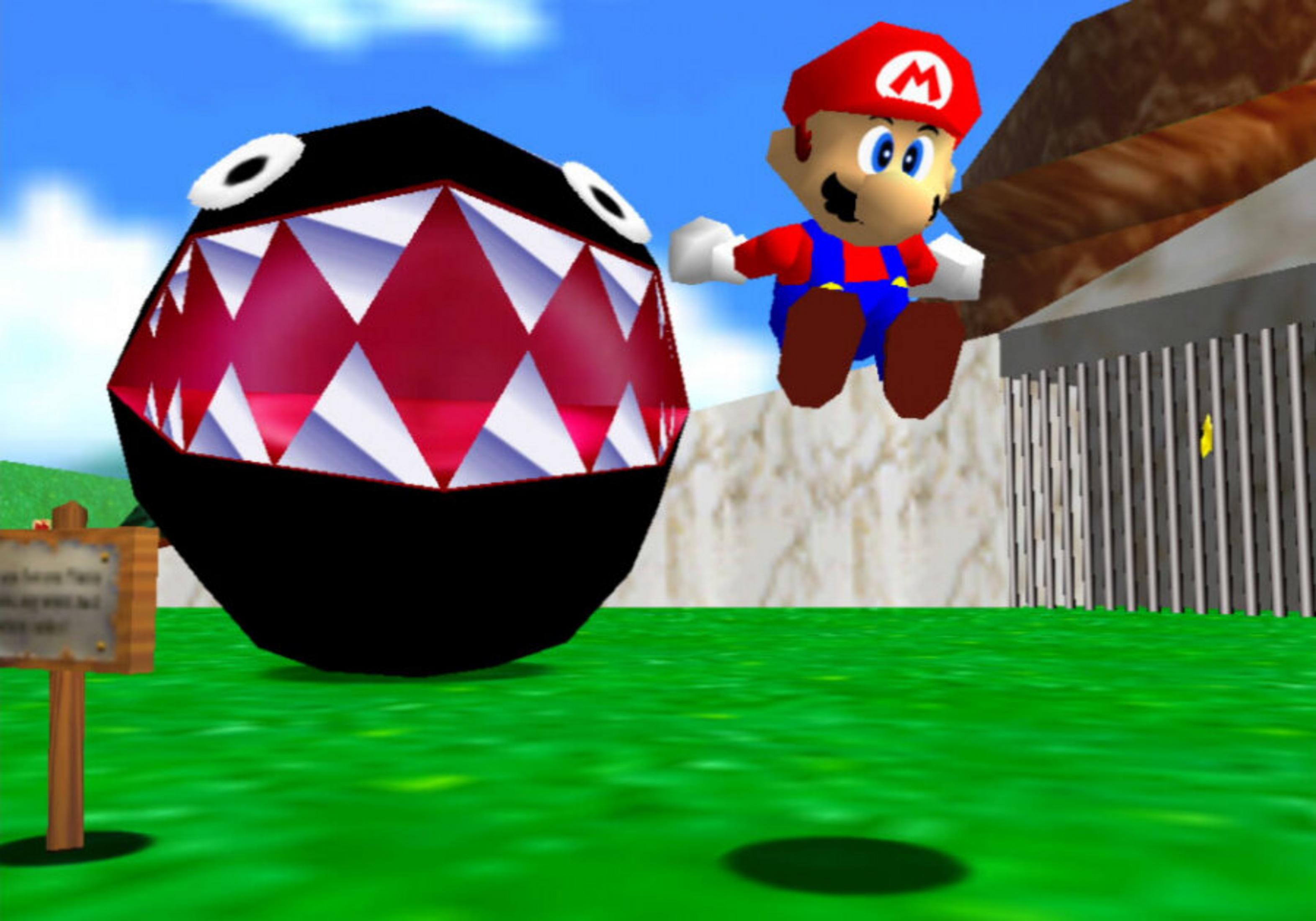 Mario salta vicino a un Chain Chomp. Un cartello è a sinistra. Una recinzione e un muro a destra. Cielo blu.