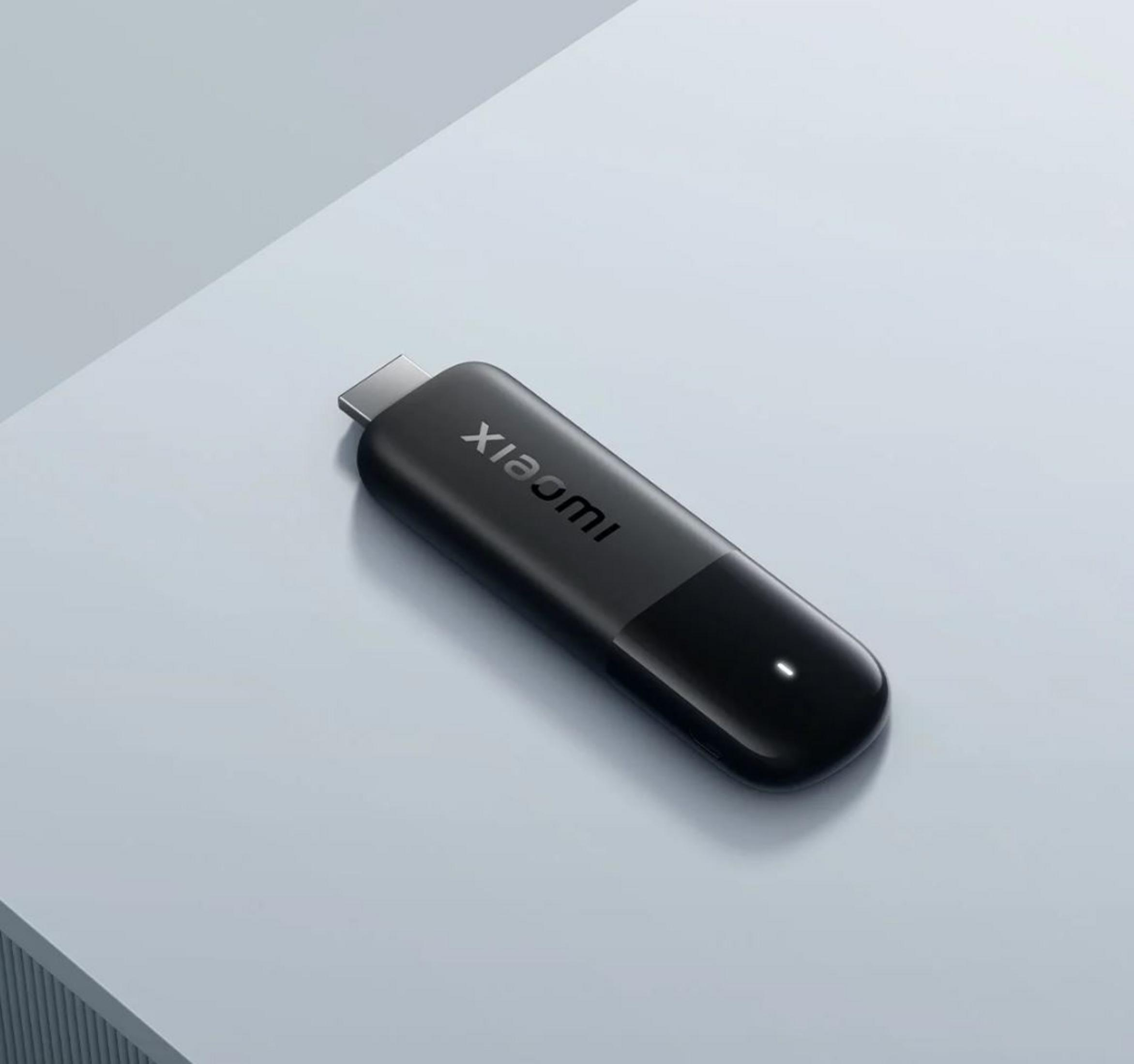 Un dispositivo de transmisión Xiaomi negro sobre superficie azul claro, con la marca visible.