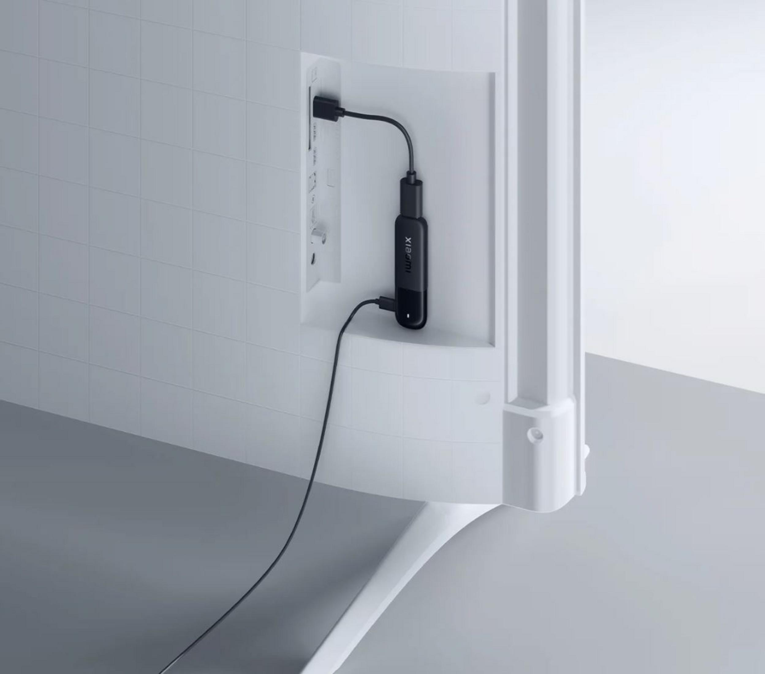 Parte trasera de TV blanca con dispositivo negro enchufado. Cable negro conecta el dispositivo.