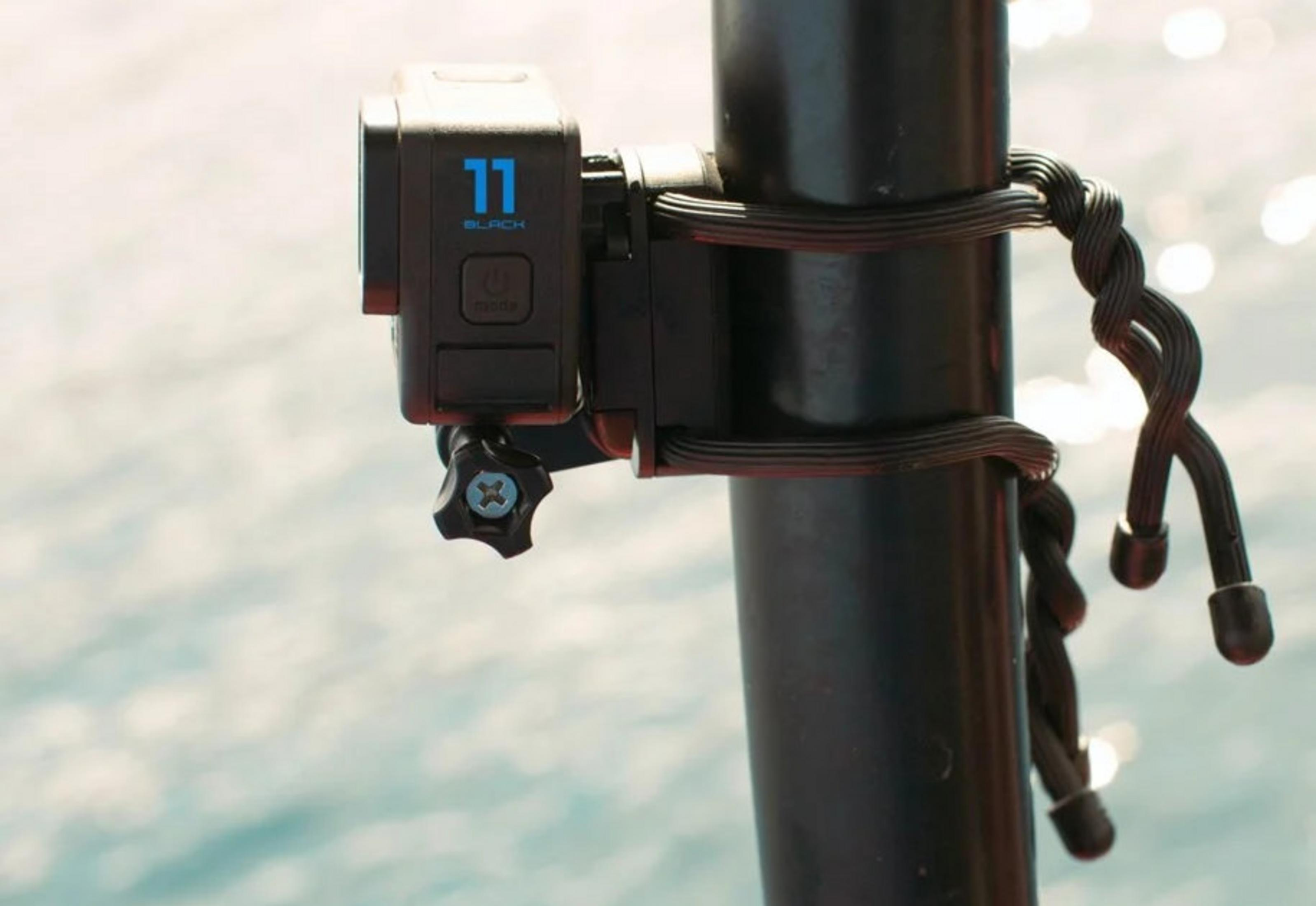 Czarna kamera GoPro jest zamontowana na czarnym słupie z czarnym paskiem. W tle widać rozmyty wodę.