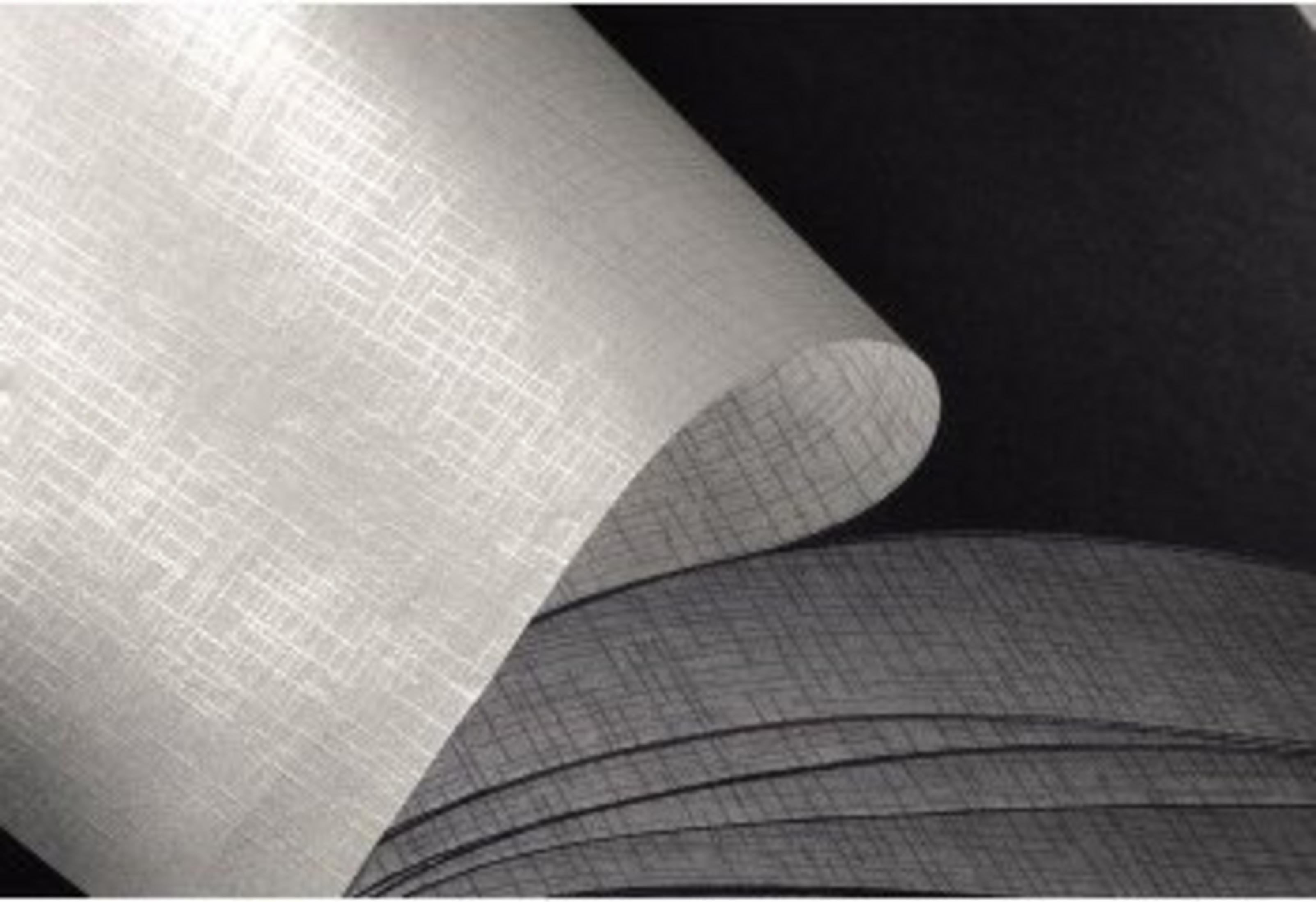 Zbliżenie zwiniętej, teksturowanej, jasnej tkaniny z ciemniejszą, wzorzystą tkaniną widoczną w tle.