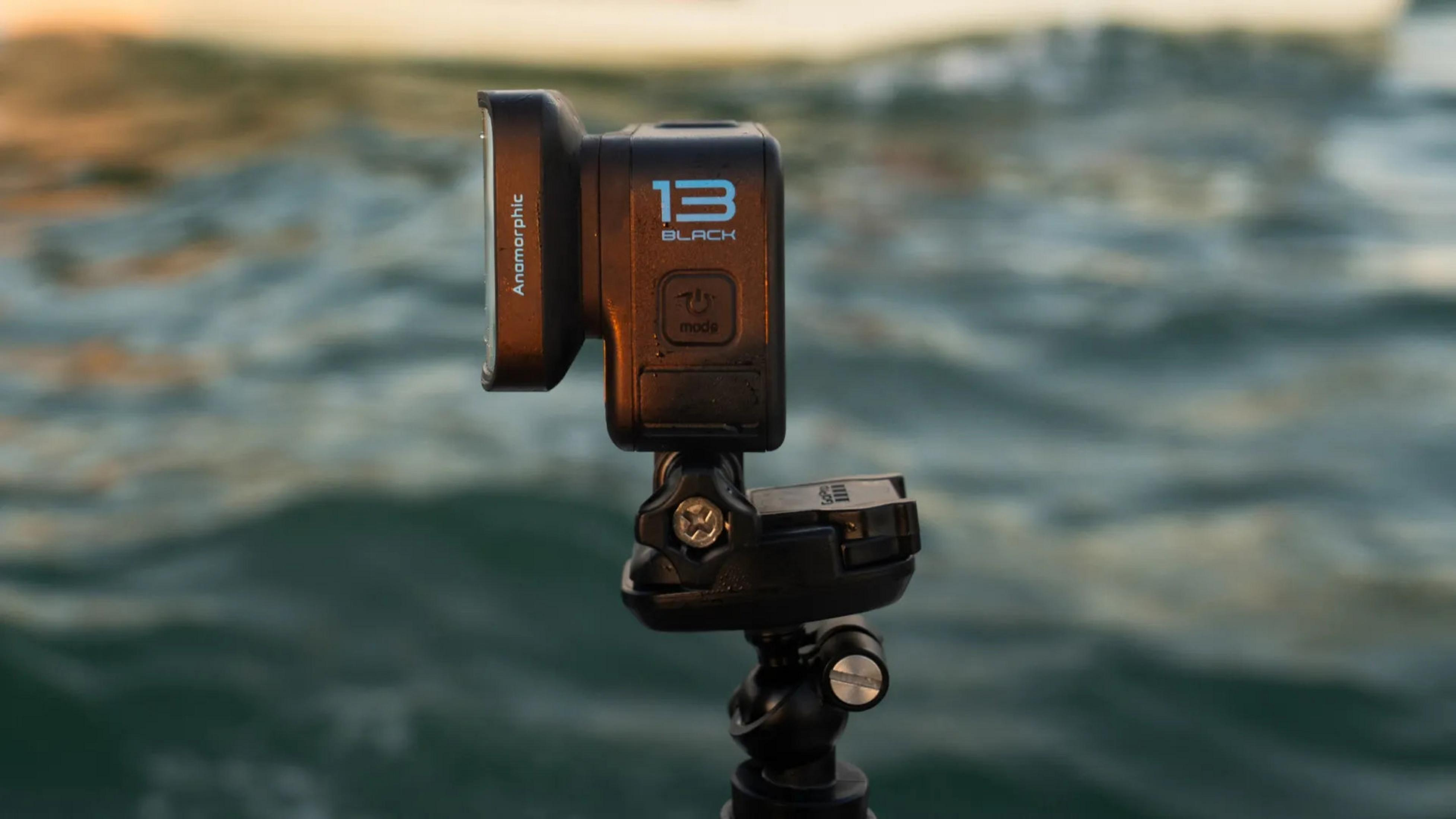 Eine schwarze GoPro-Kamera mit Anamorphotobjektiv ist auf einem Stativ montiert. Der Hintergrund zeigt Ozeanwasser.