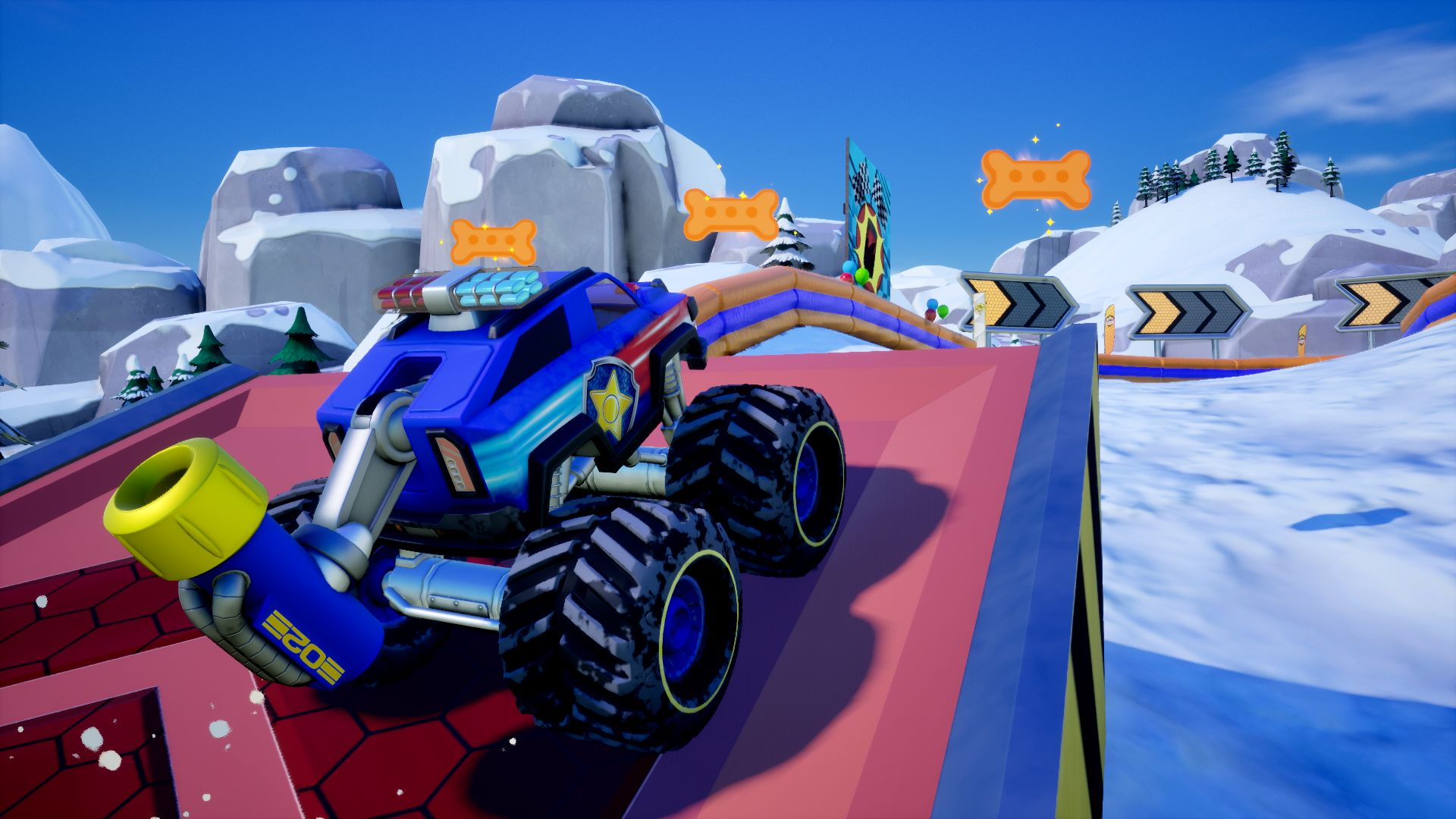 Ein blauer Monstertruck mit großen Reifen steht auf einer roten Rampe. Es gibt knochenförmige Schilder und einen schneebedeckten Berg im Hintergrund.