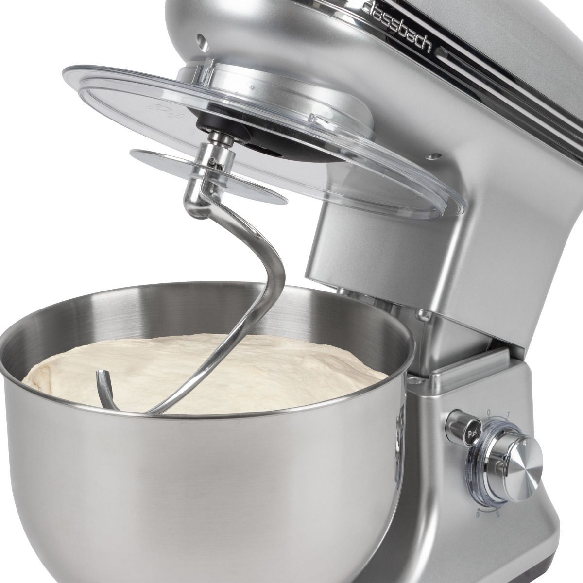 Srebrny mikser stojący z ciastem w misce. Przezroczysta osłona jest otwarta. Ramię miksera jest w cieście.