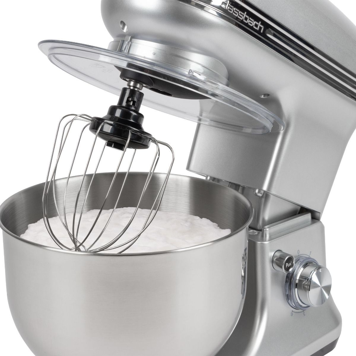 Srebrny mikser stojący z końcówką do ubijania. Misa jest wypełniona białymi składnikami. Mikser jest na białym tle.