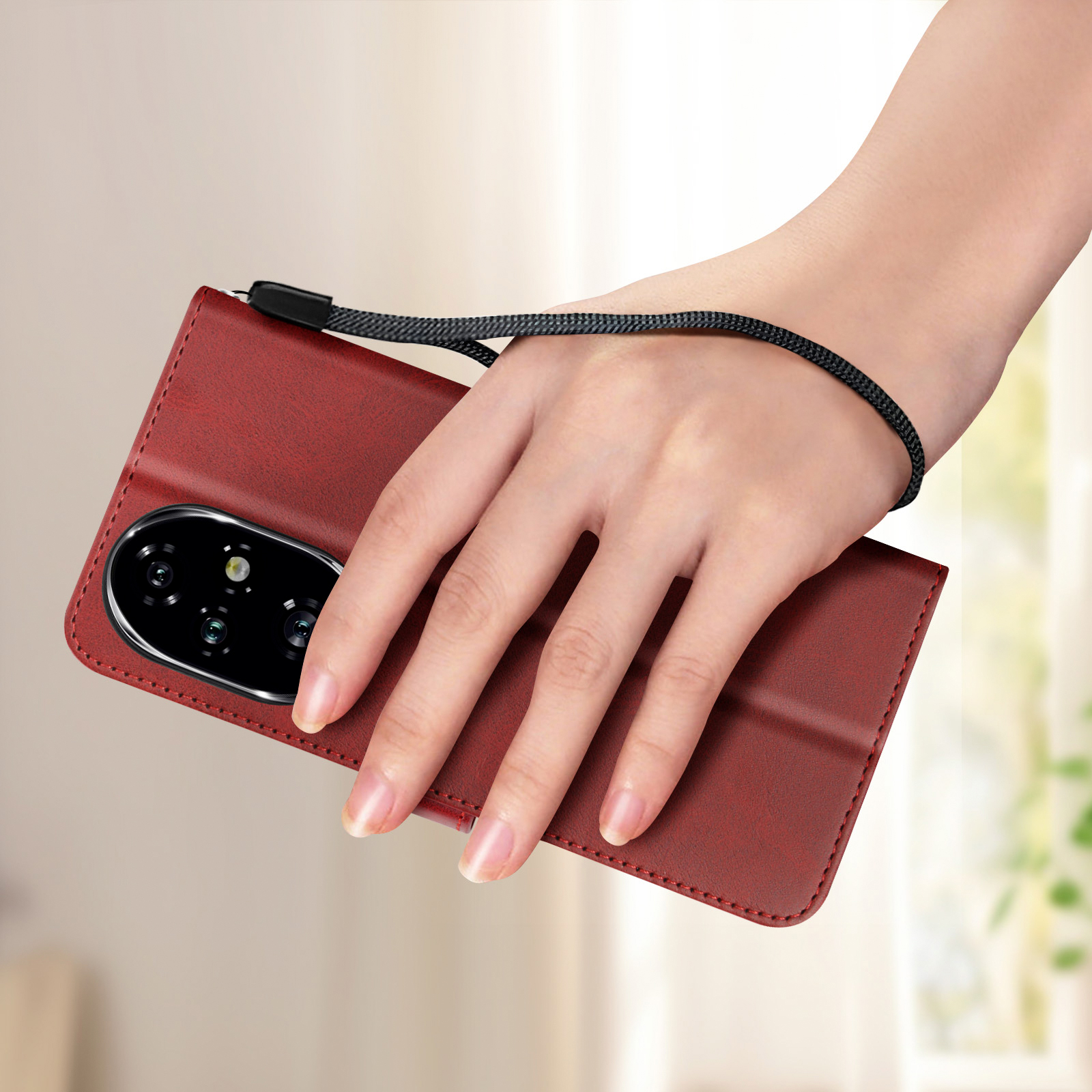 Mano che tiene una custodia rossa per telefono con cinturino nero. La custodia ha un modulo fotocamera. Sfondo sfocato.
