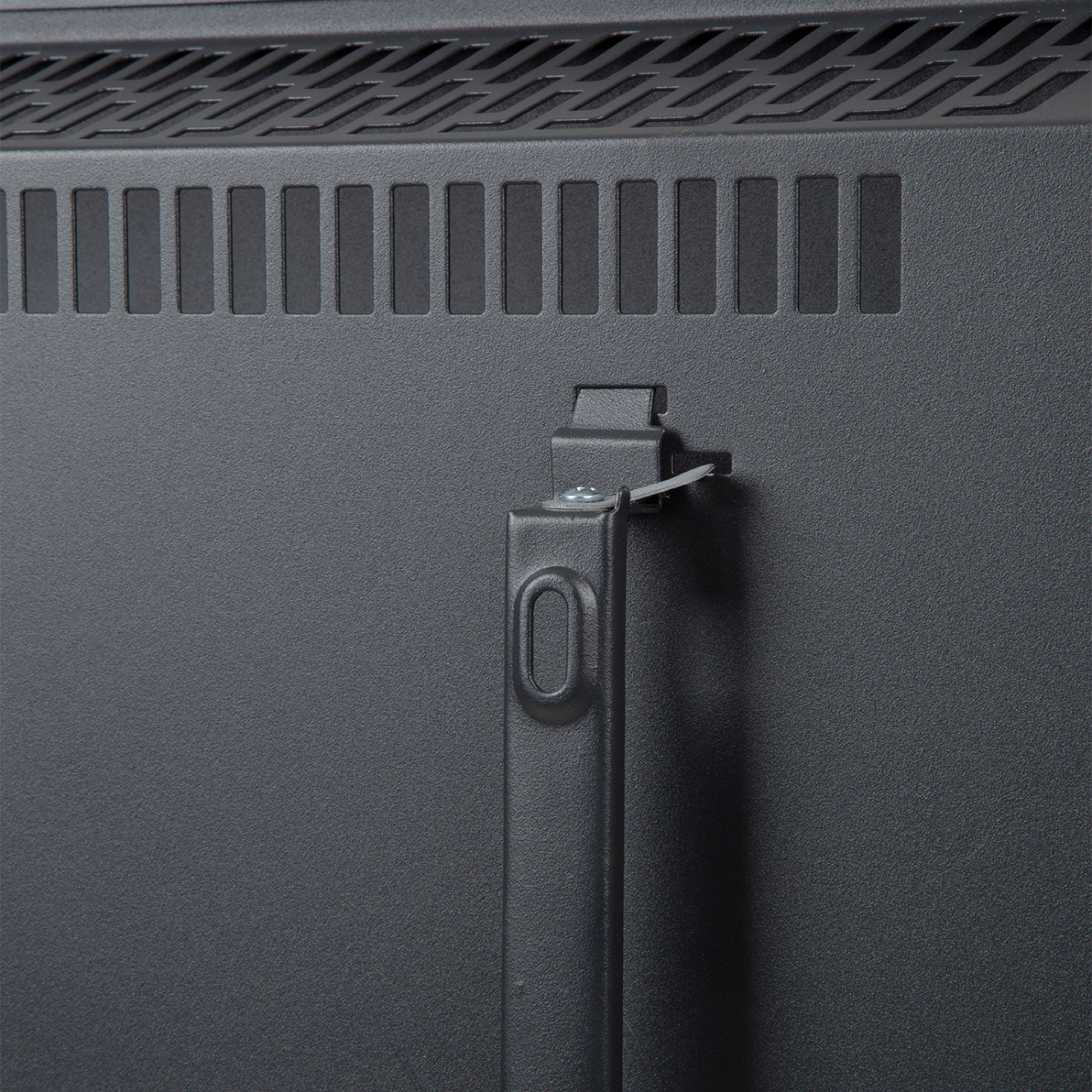 Primer plano de la parte trasera de un electrodoméstico gris oscuro con ventilaciones, un asa y un soporte metálico.