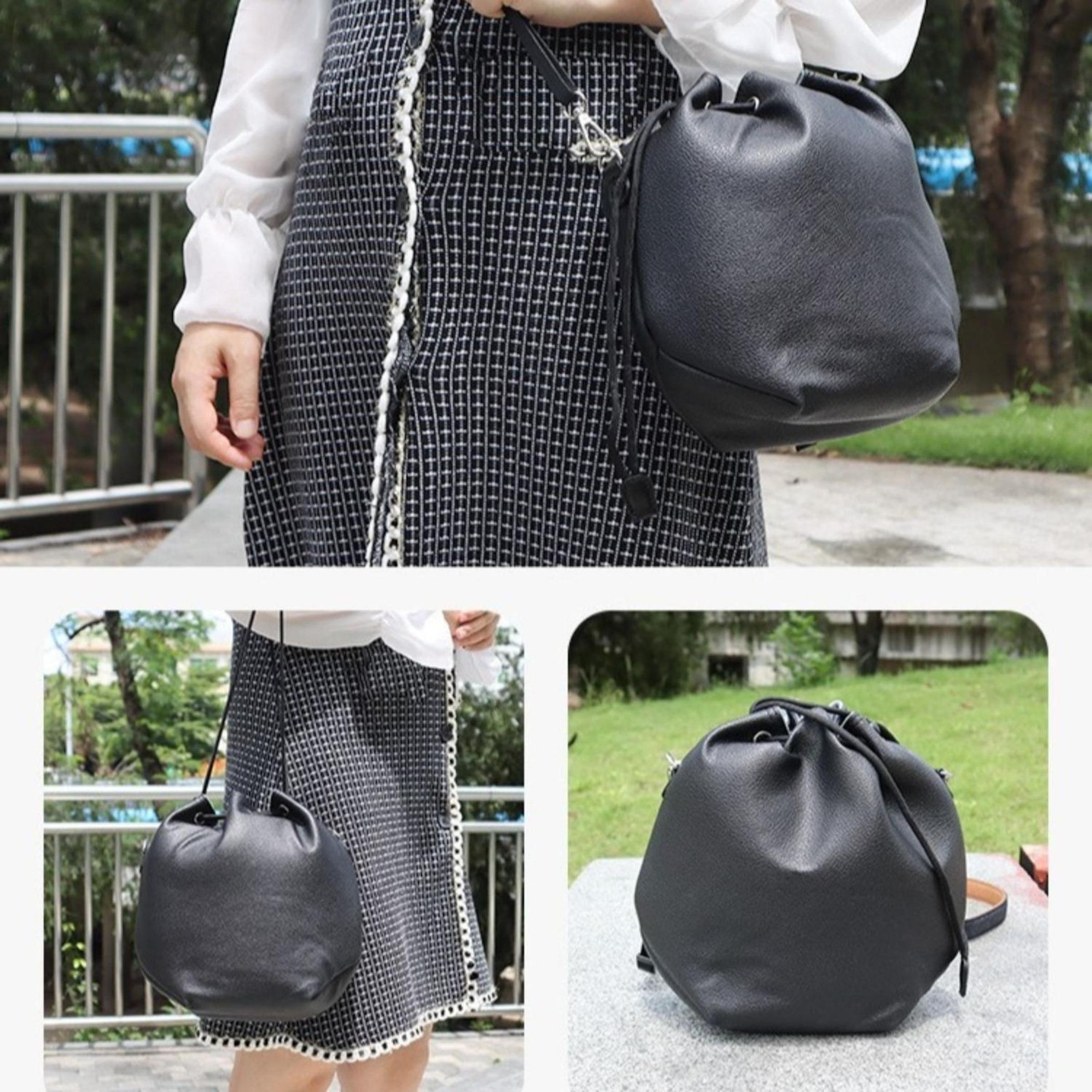 Eine Frau trägt ein schwarz-weiß kariertes Kleid und hält eine schwarze Leder-Eimertasche. Eine zweite Tasche ist sichtbar.