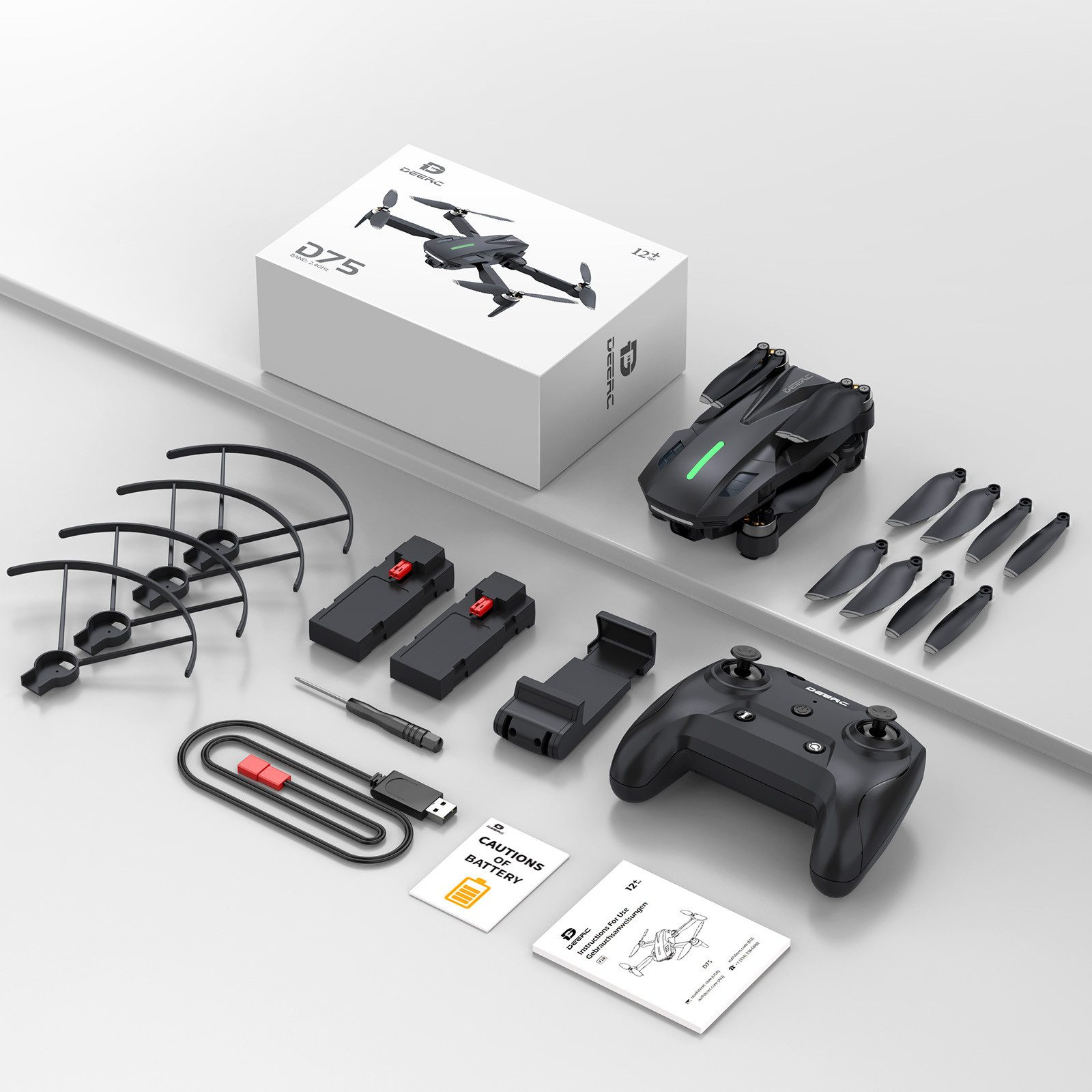 Ein Drohnen-Kit mit schwarzer Drohne, Controller, Propellern, Akku, Ladegerät und einer Box, alles auf weißer Oberfläche.
