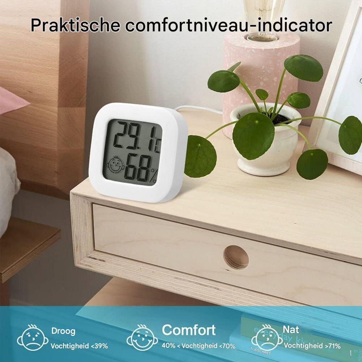 Ein weißes digitales Thermometer mit Temperatur- und Feuchtigkeitsanzeige steht auf einem hölzernen Nachttisch mit einer Topfpflanze. Komfort-Symbole sind unten.