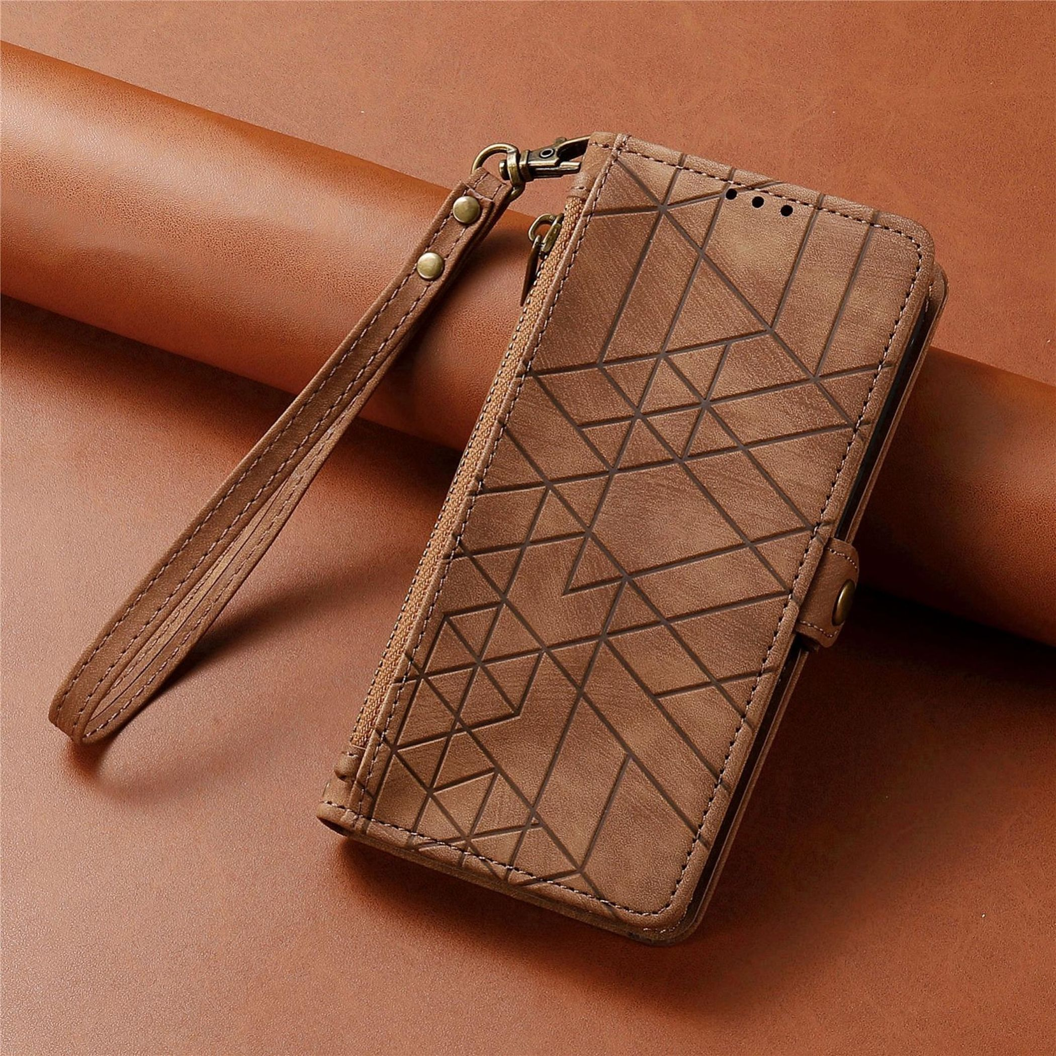 Braune Leder-Handyhülle mit geometrischem Muster, Handschlaufe und Reißverschluss auf brauner Lederoberfläche.