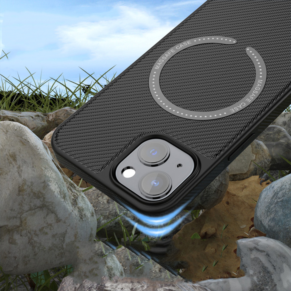 Eine schwarze Handyhülle mit MagSafe-Ring, zwischen Felsen und Gras unter blauem Himmel.