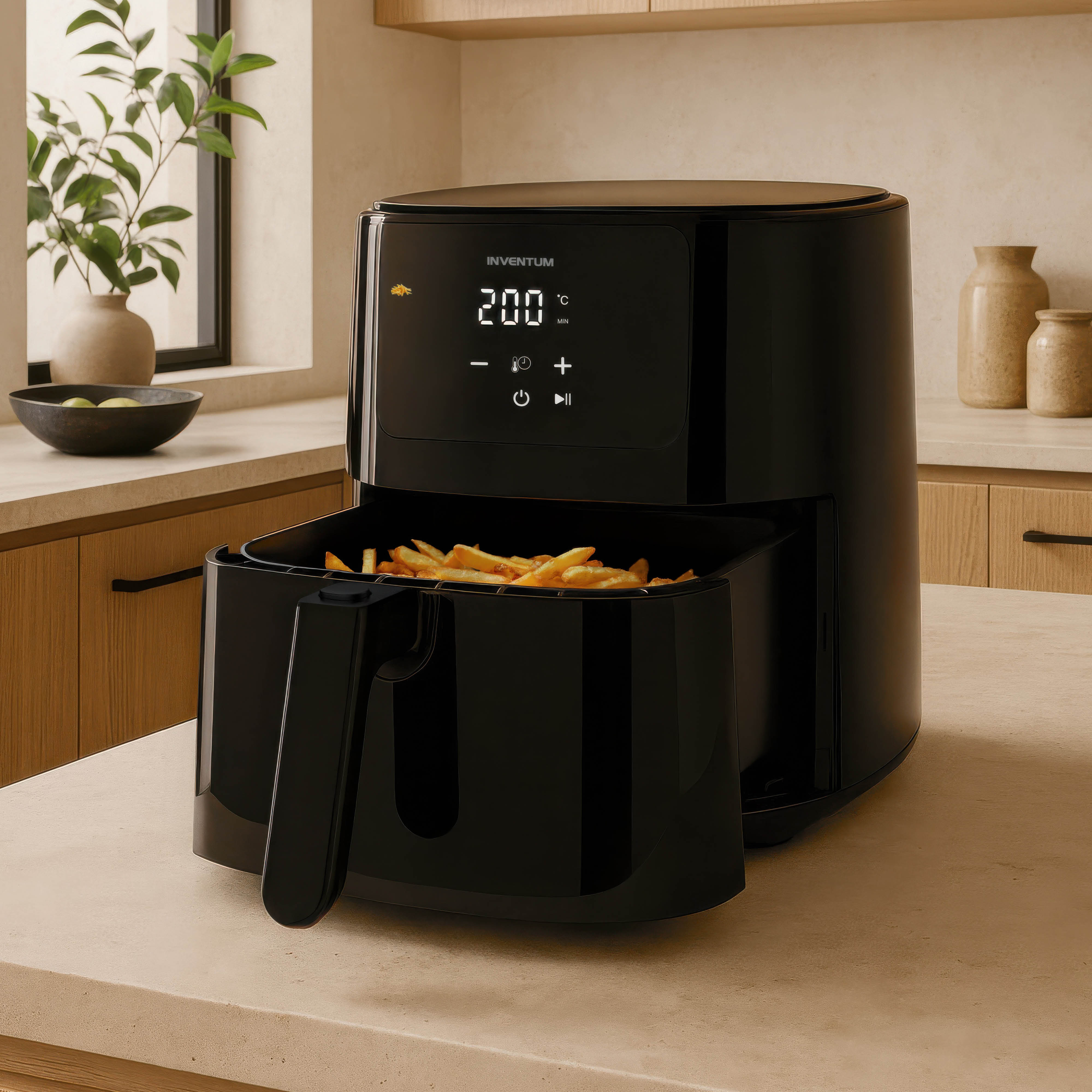 Zwarte airfryer met friet. Keuken met planten, vazen en houten kasten.