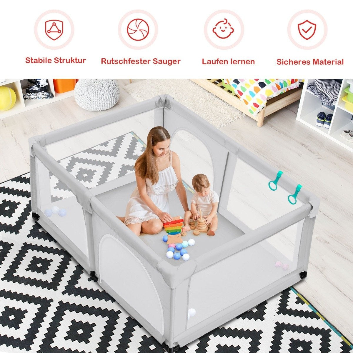 Een vrouw en een baby zitten in een box. Er liggen speeltjes verspreid. De box staat op een patroonkleed.