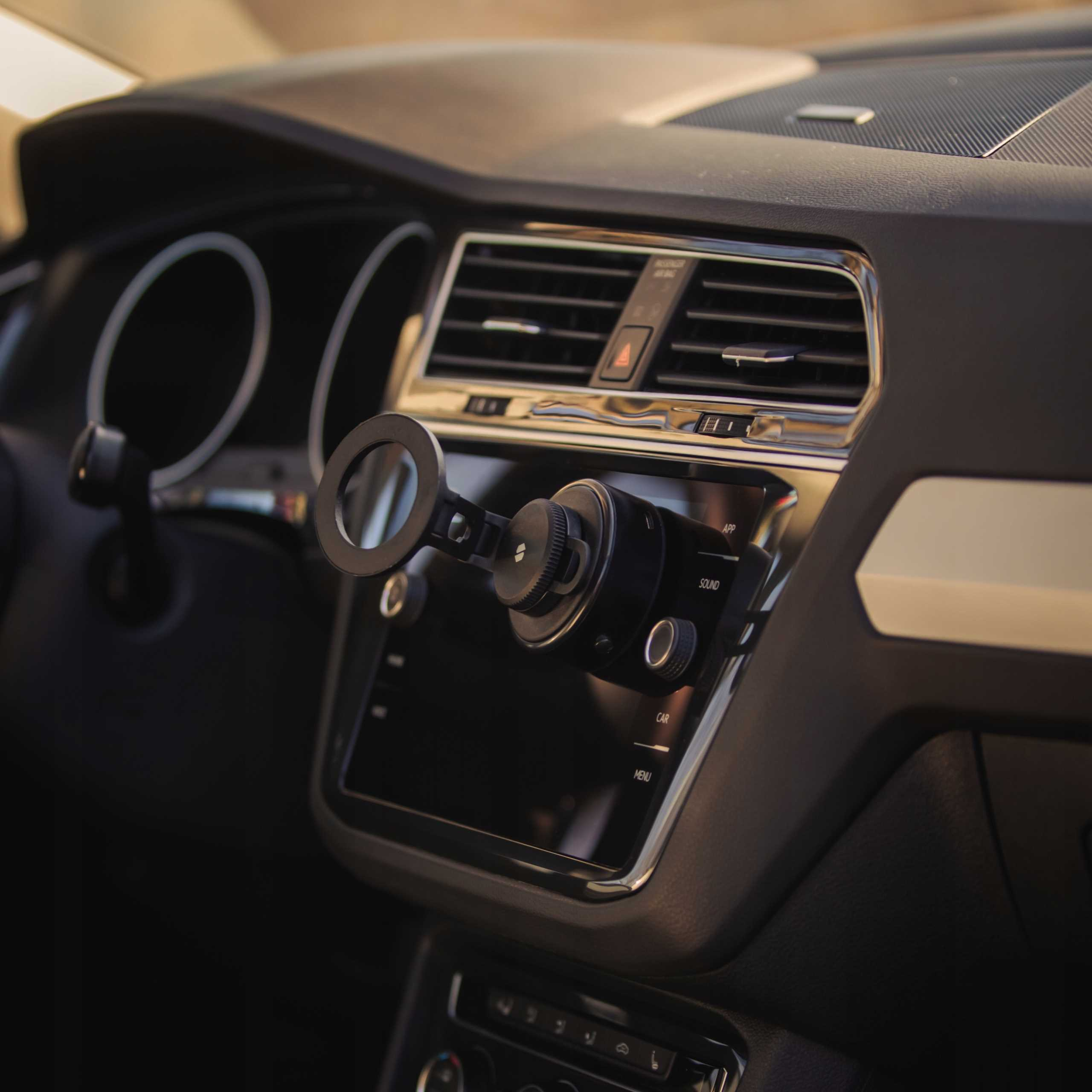 Wnętrze samochodu. Zamontowano uchwyt na telefon. Deska rozdzielcza ma otwory wentylacyjne, ekran i przyciski.