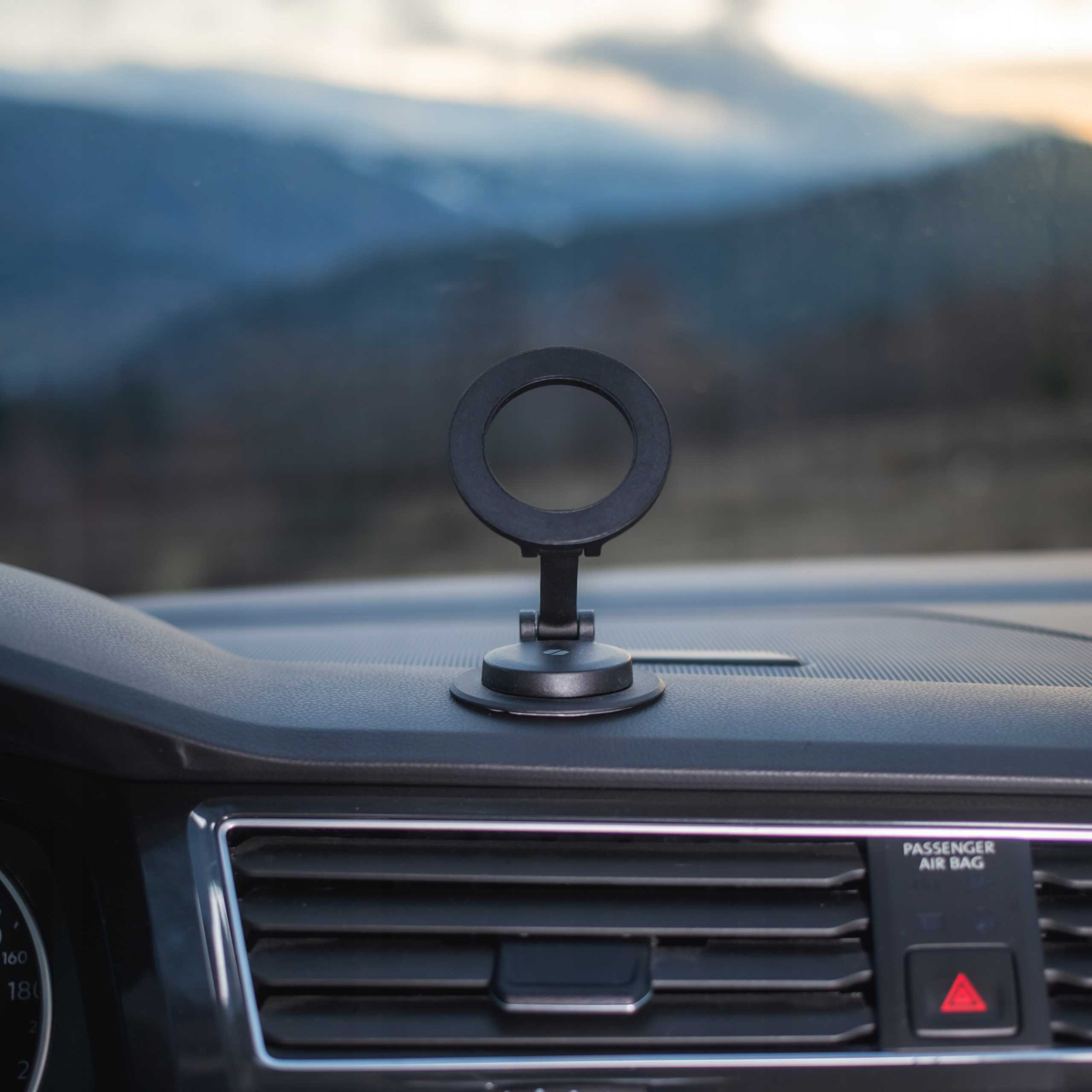 Wnętrze samochodu z uchwytem na telefon. W tle widoczne góry. Włączone światła awaryjne.