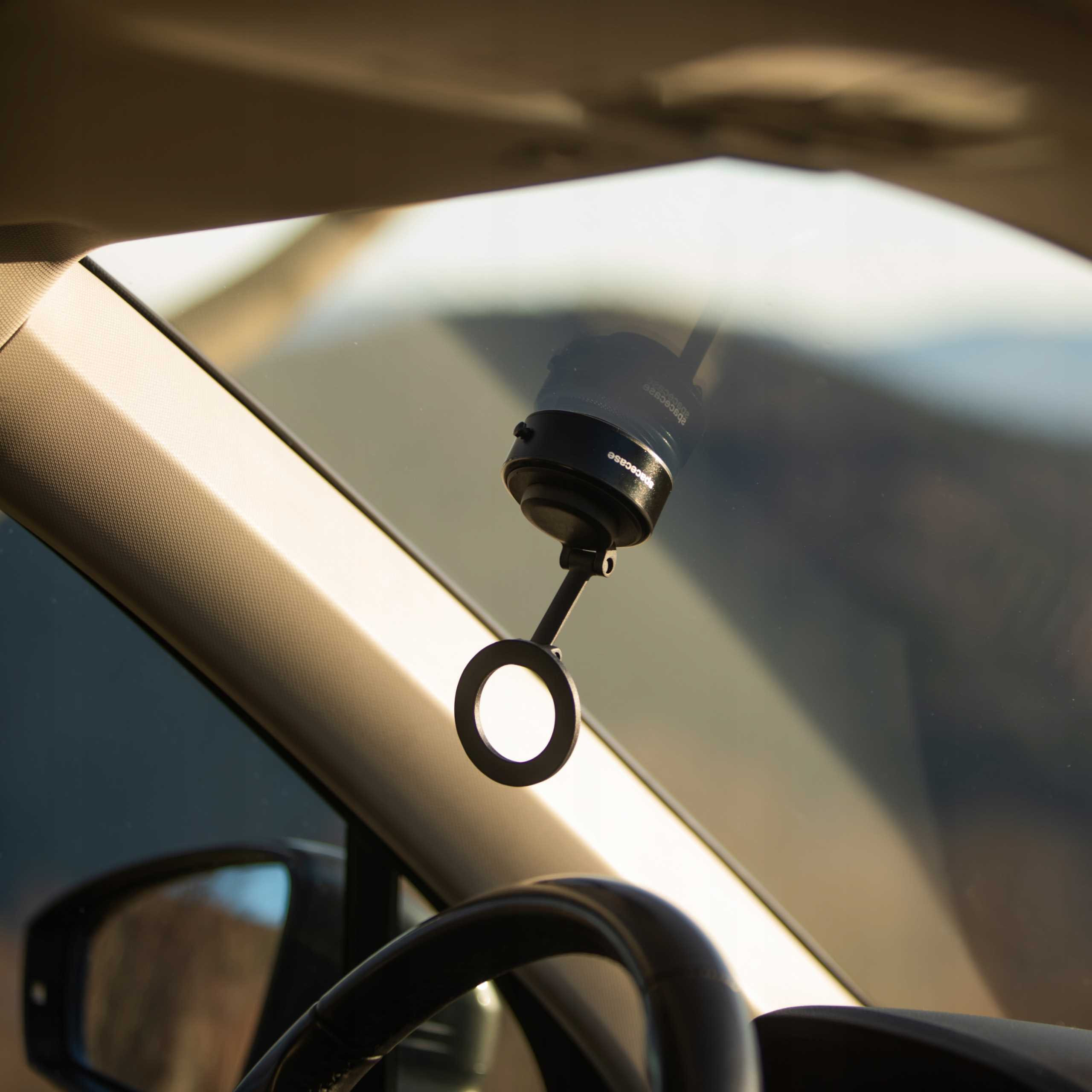 Wnętrze samochodu z urządzeniem przymocowanym do przedniej szyby. Urządzenie ma okrągły element.