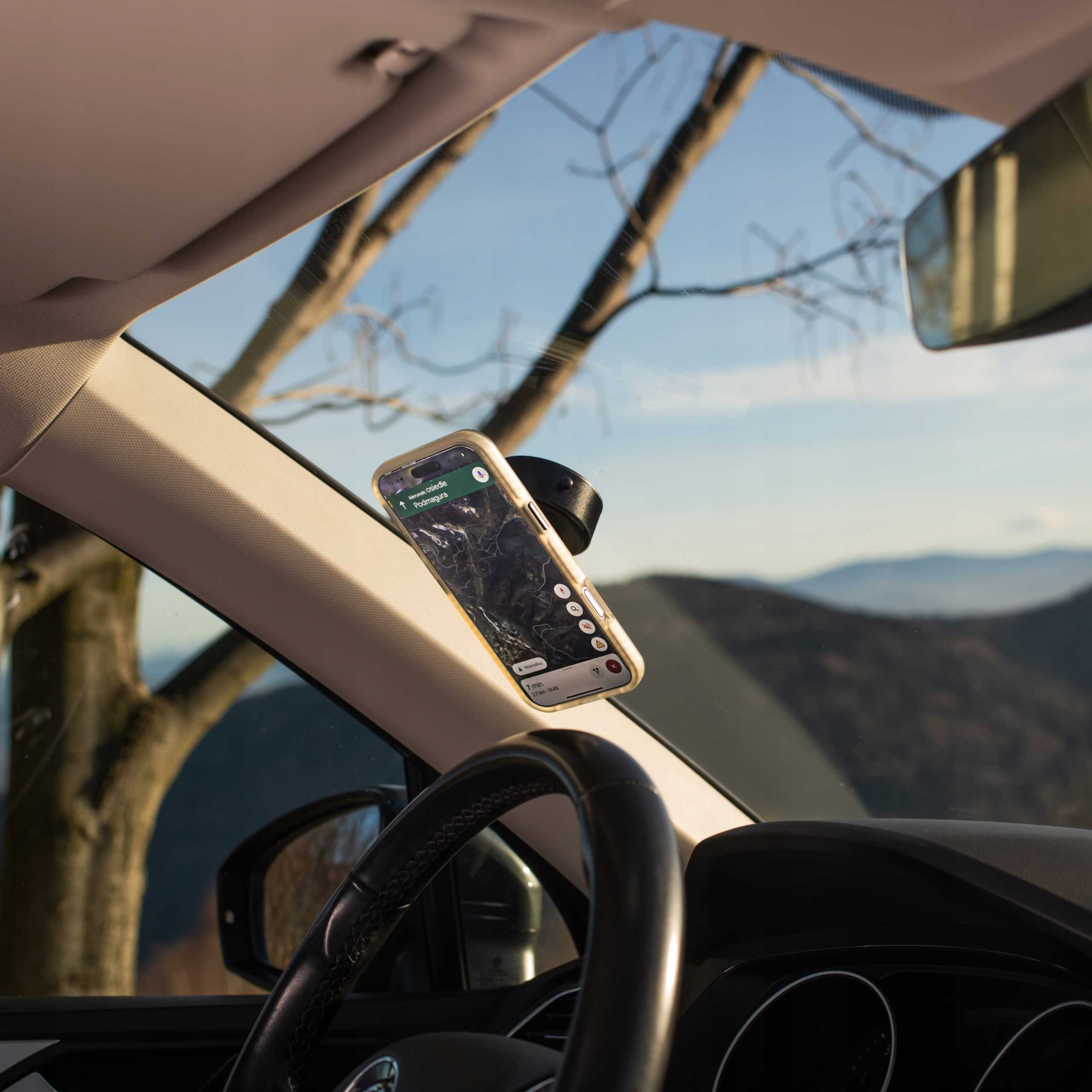 Telefon z nawigacją jest zamontowany w samochodzie. Góry widoczne przez przednią szybę. Kierownica jest na dole.