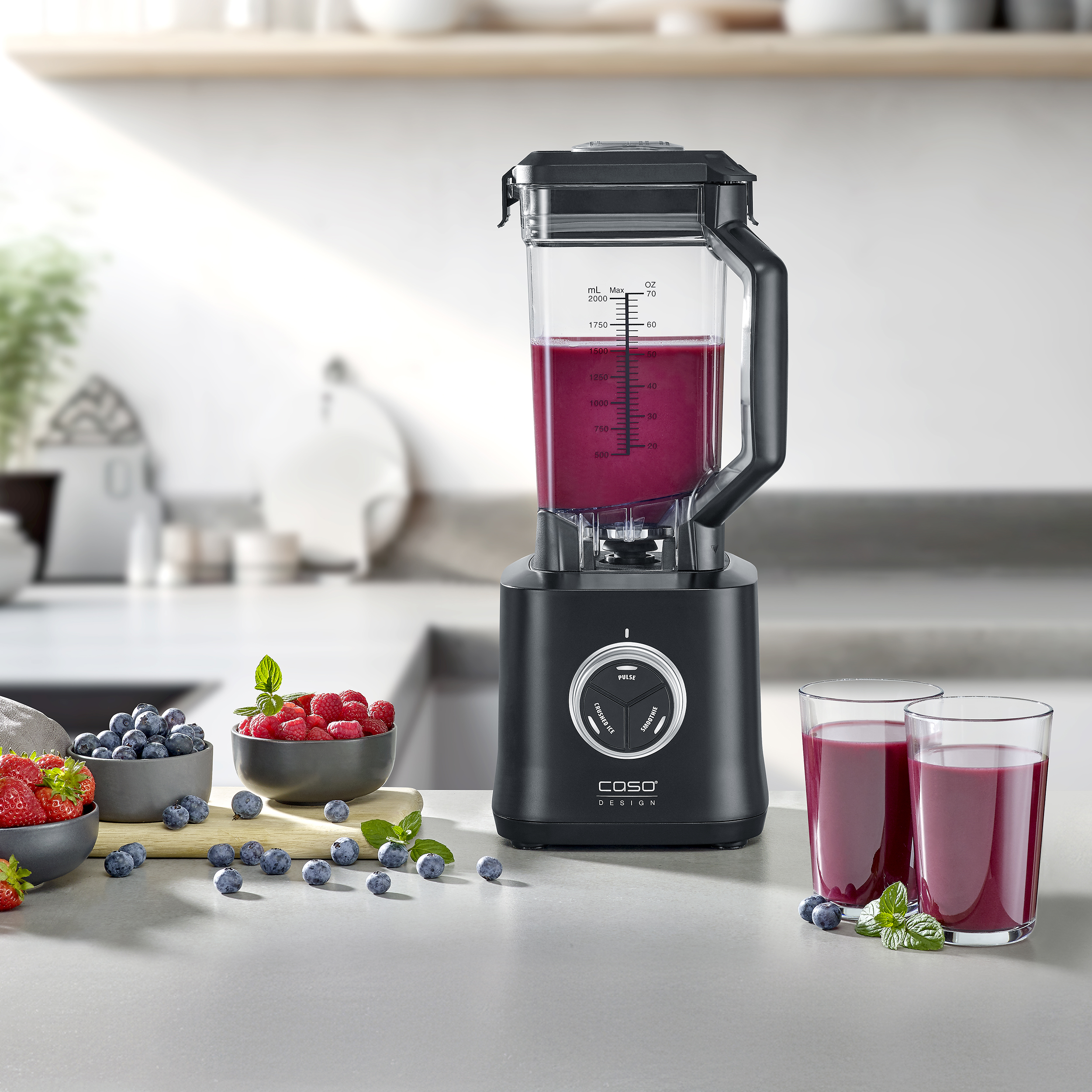 Un frullatore con succo, bacche e due bicchieri di succo. La scena si svolge in una cucina.