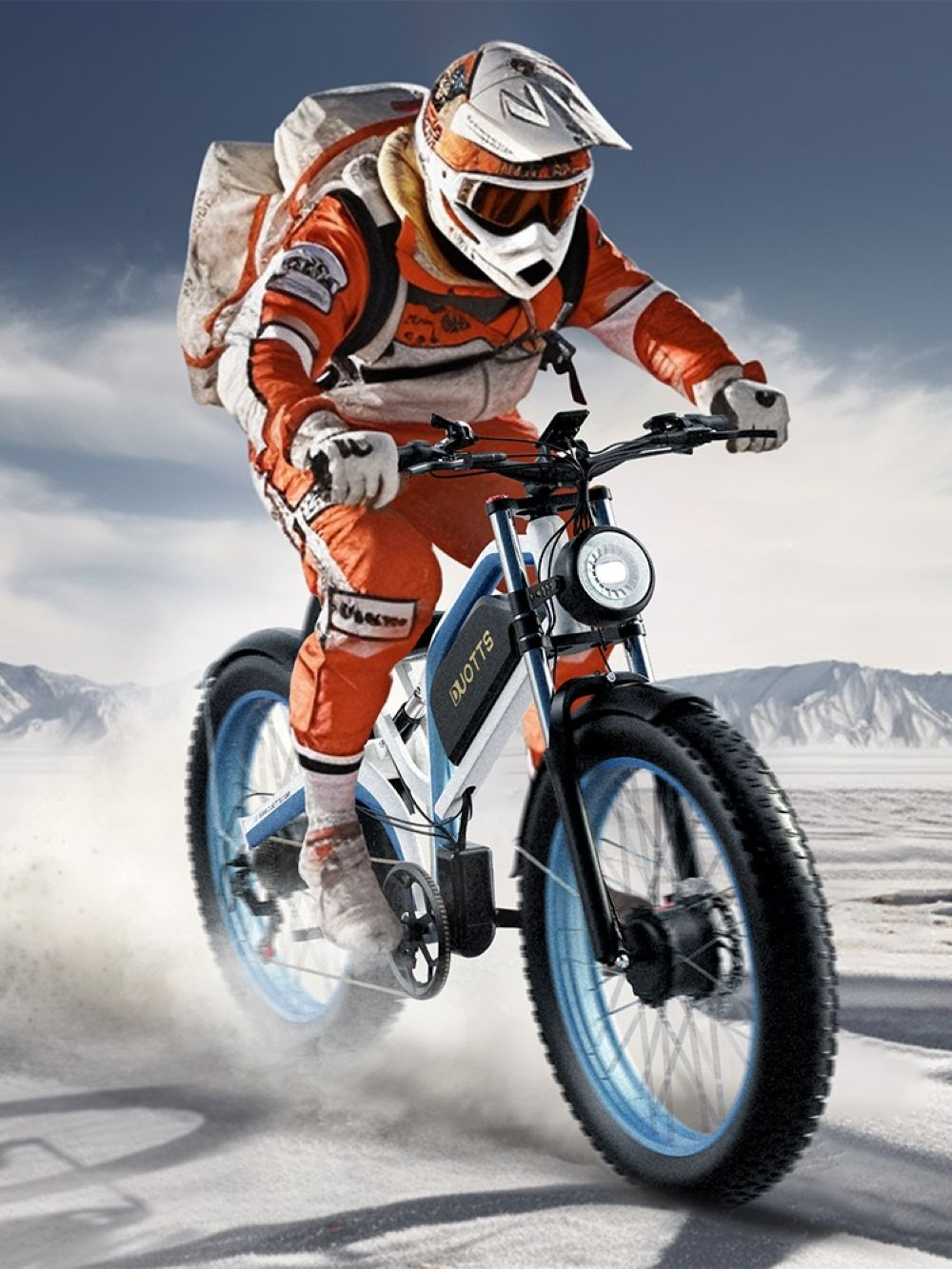 Una persona con traje naranja y casco blanco monta una bicicleta de llantas gordas sobre nieve. Montañas y cielo azul al fondo.