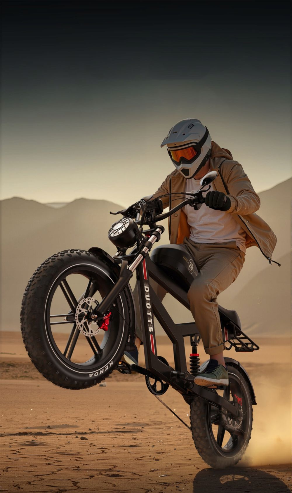 Una persona en una motocicleta negra hace un caballito en un desierto. La motocicleta tiene la marca DUOTTS. La persona lleva un casco.