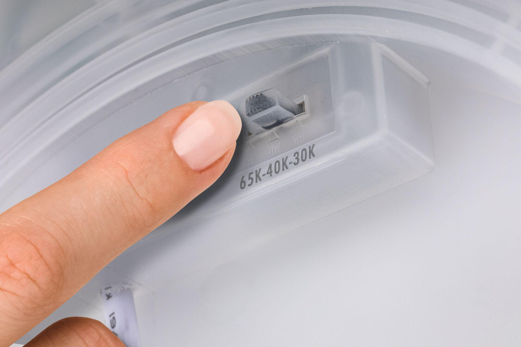 Palec dotyka przełącznika na białym urządzeniu. Przełącznik jest oznaczony 65K-40K-30K. Tło jest białe i szare.