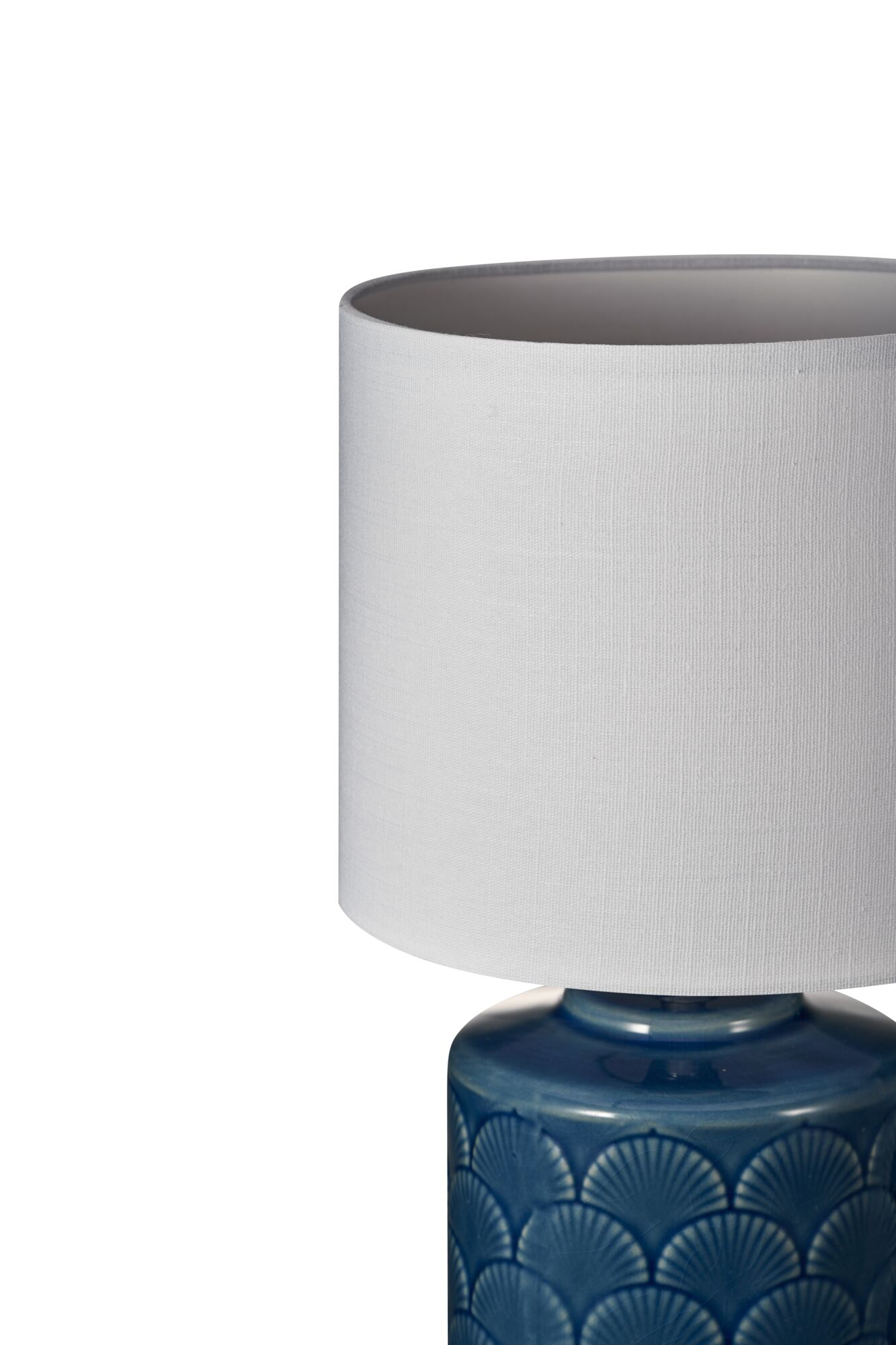 Niebieska lampa ceramiczna z białym abażurem na białym tle. Podstawa lampy ma dekoracyjny wzór.