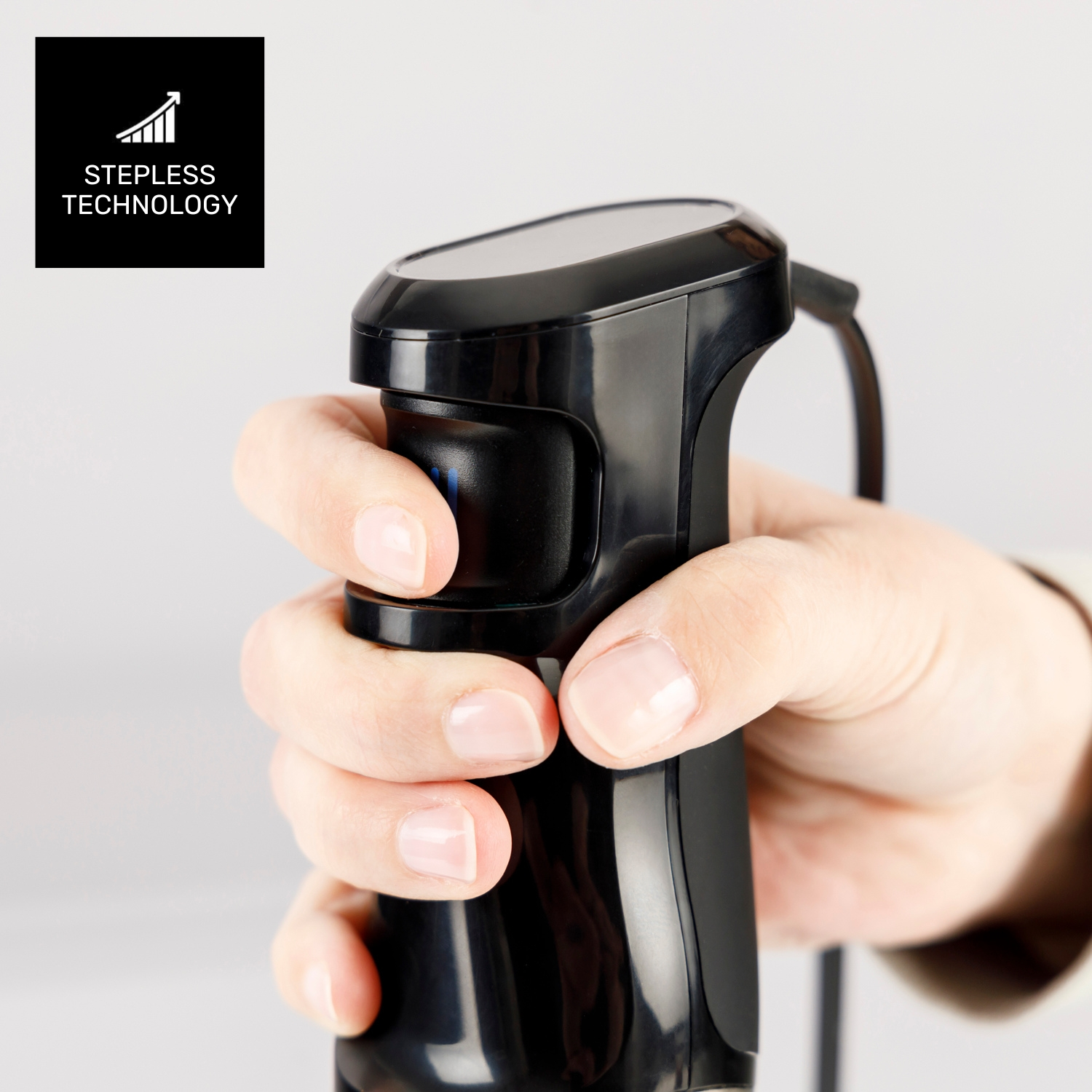 Una mano sosteniendo un electrodoméstico de cocina negro. Un cuadrado negro con las palabras 'Stepless Technology' está en la esquina superior izquierda.