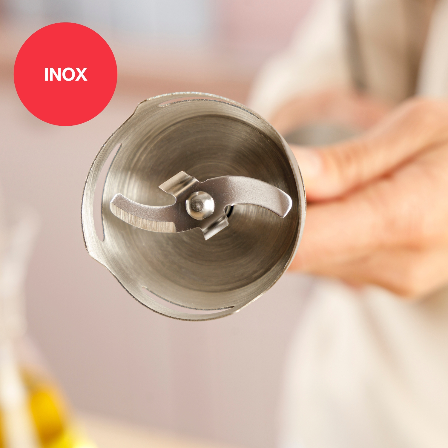 Primer plano de una cuchilla de licuadora. La cuchilla es plateada, con un círculo rojo y texto blanco 'INOX' en la esquina superior izquierda.