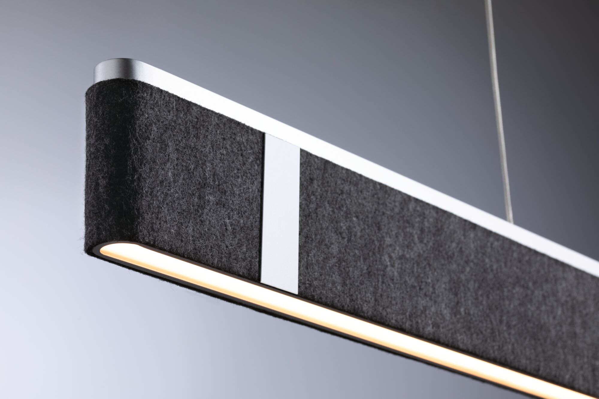Nowoczesna, prostokątna lampa wisząca z ciemnoszarym, filcowym wykończeniem, białymi akcentami i jasnym paskiem światła.