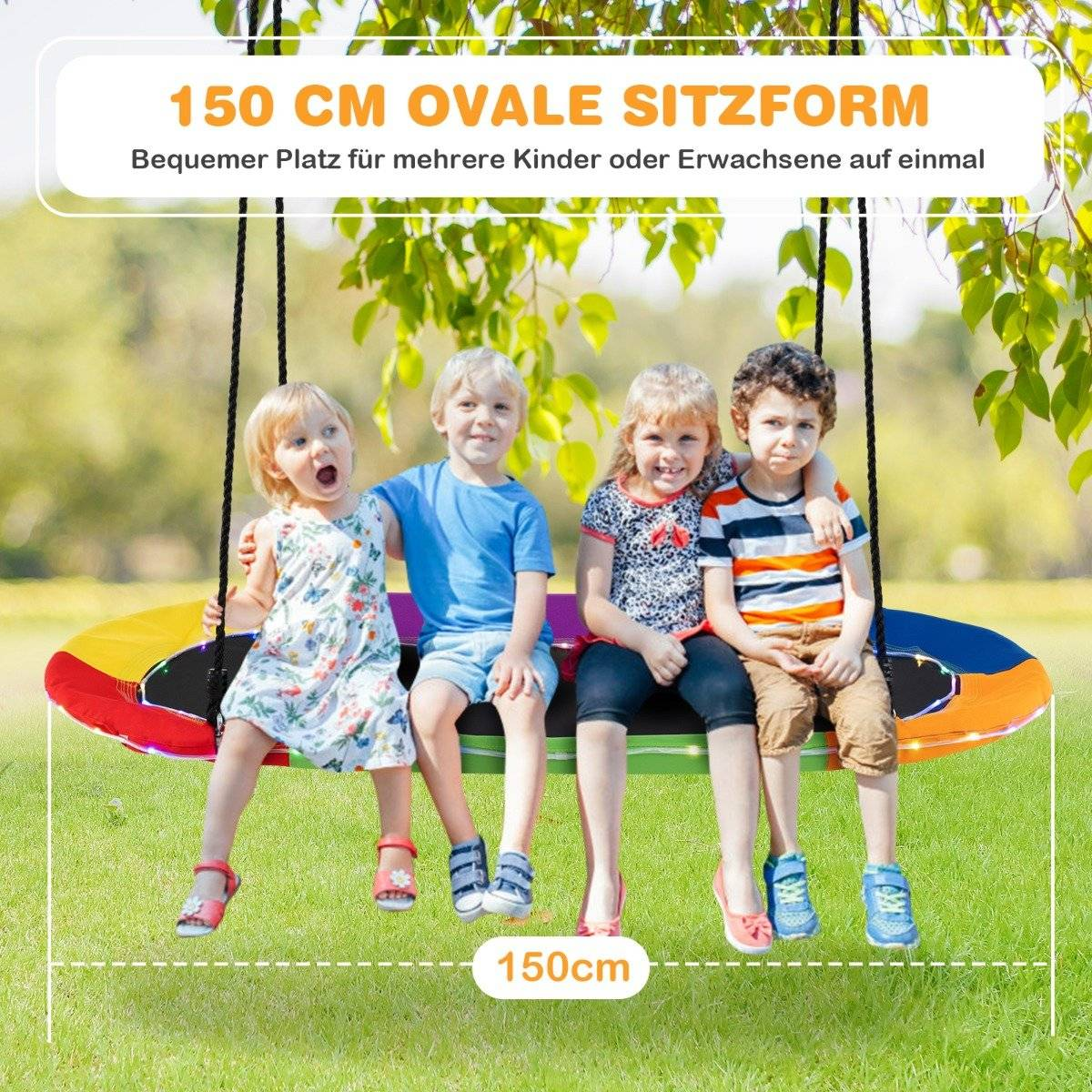 Cuatro niños sentados en un columpio en un parque. Sonriendo. El columpio es ovalado con diseño colorido. Hierba verde en el fondo.