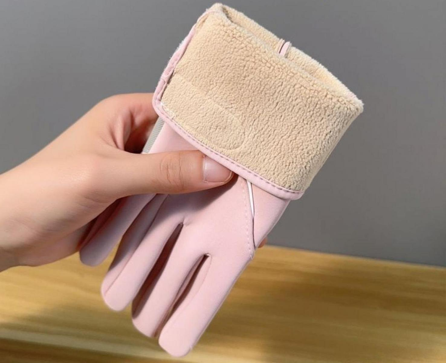 Eine Hand hält einen rosa Handschuh mit beigefarbenem, flauschigem Bündchen. Der Hintergrund ist ein verschwommenes Grau. Der Handschuh ist detailliert.