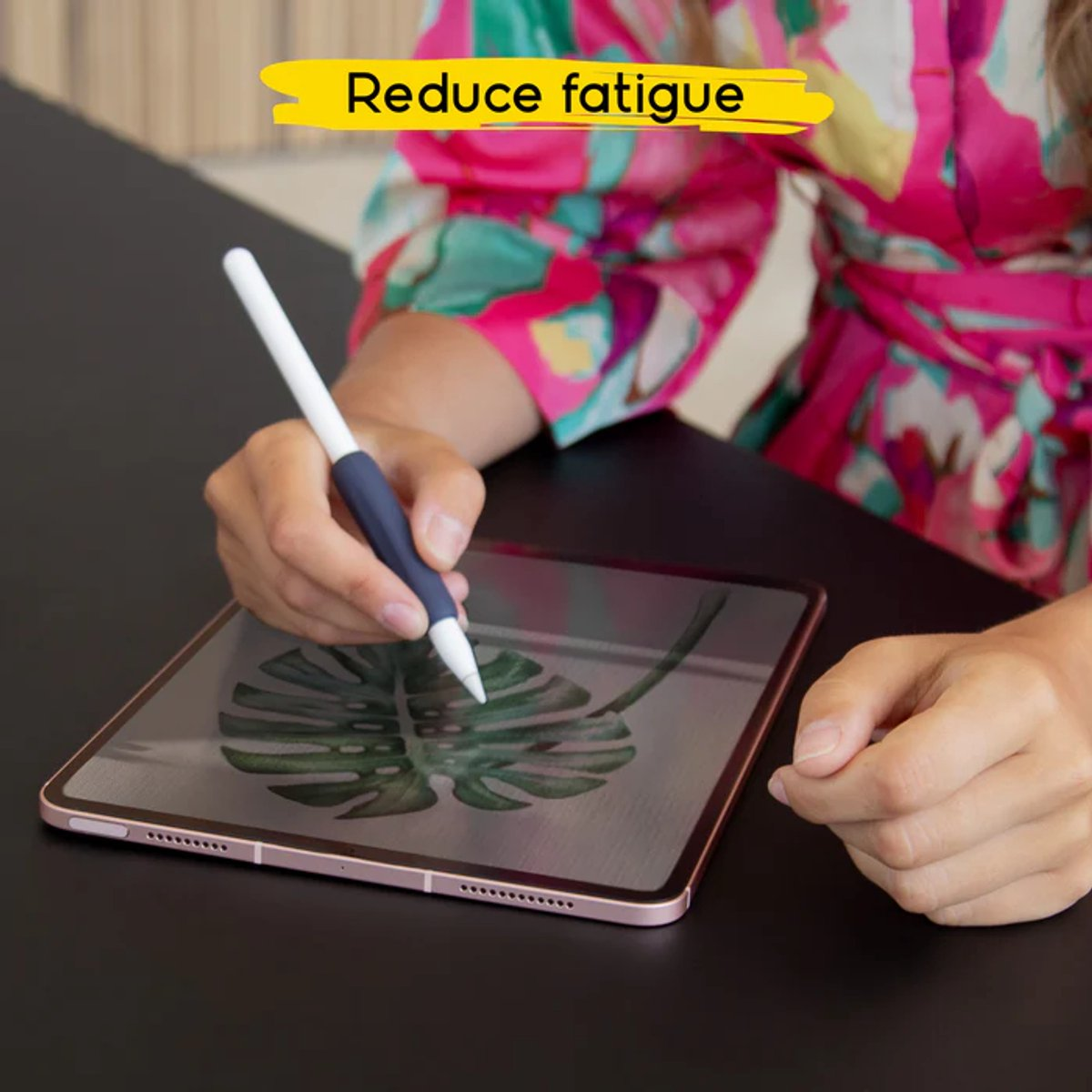 Una persona usa un lápiz óptico con agarre azul en una tableta. La tableta muestra un dibujo de una planta. El fondo es un vestido floral rosa.