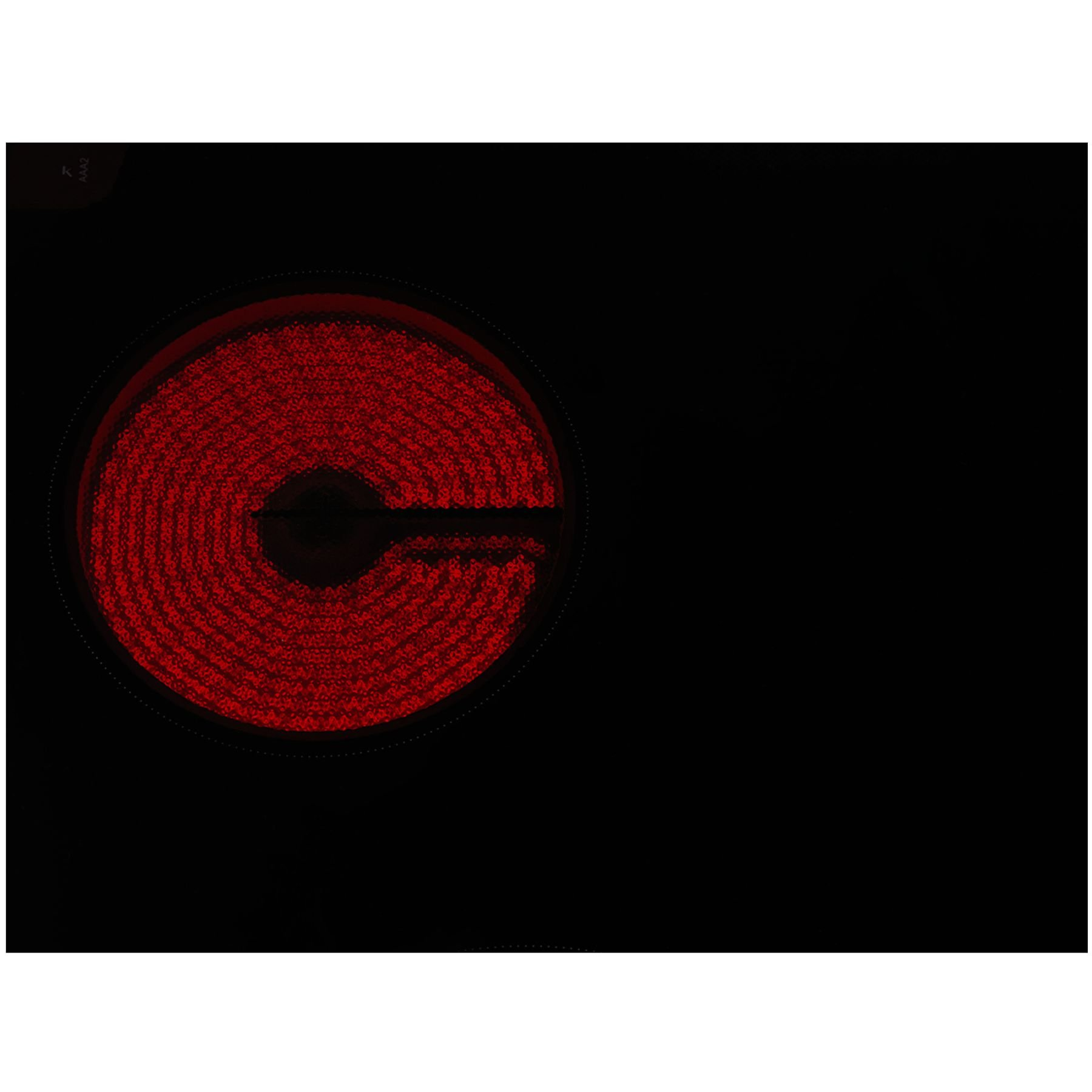 Primo piano di un piano cottura nero con un elemento riscaldante rosso incandescente. Lo sfondo è completamente nero.