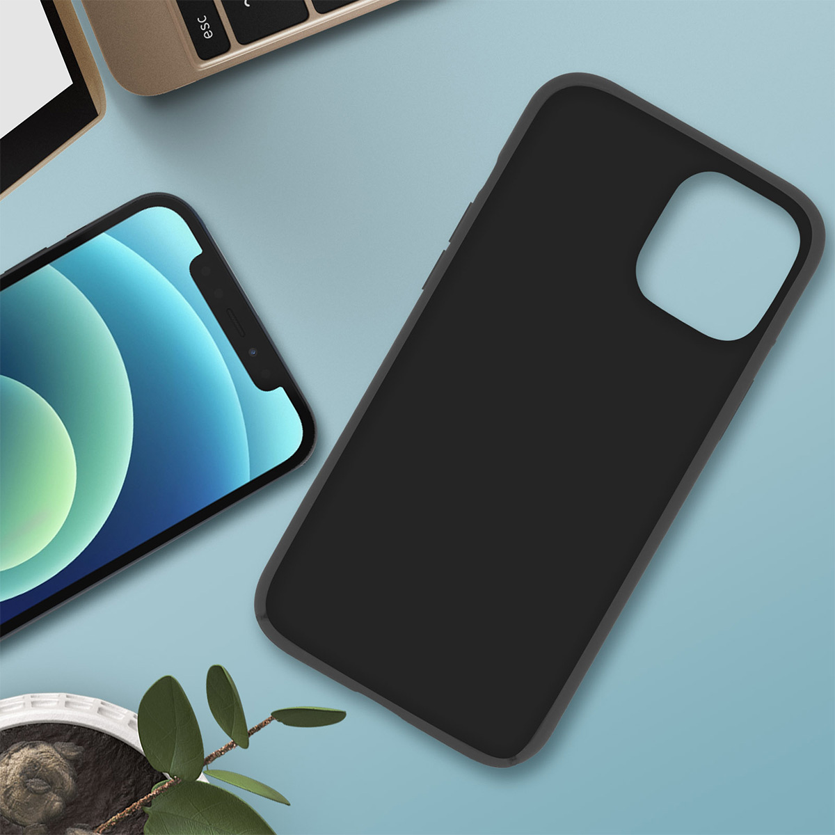 Un telefono e una custodia nera per telefono su una superficie blu, vicino a una tastiera e una pianta.