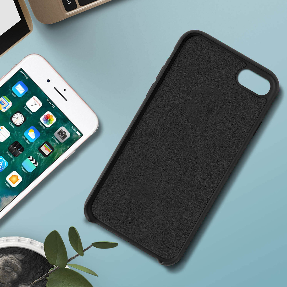 Un iPhone bianco con app è accanto a una custodia nera su una superficie blu. C'è una tastiera sullo sfondo.