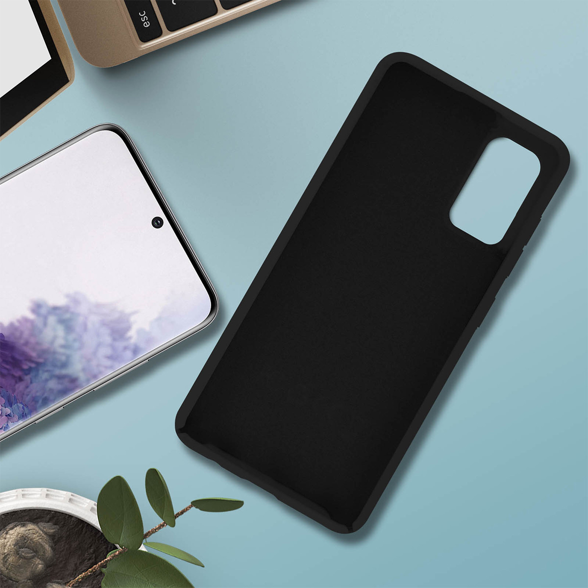 Una custodia nera per telefono e un telefono sono su una superficie azzurra. Una tastiera di laptop è sullo sfondo.