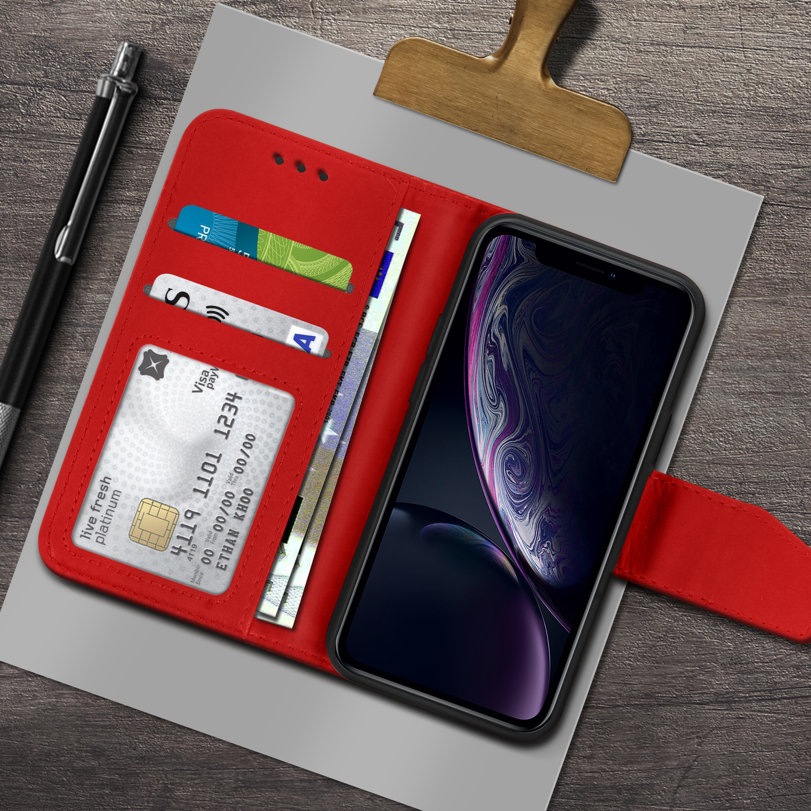 Un portafoglio rosso con telefono, carte di credito e denaro su legno.
