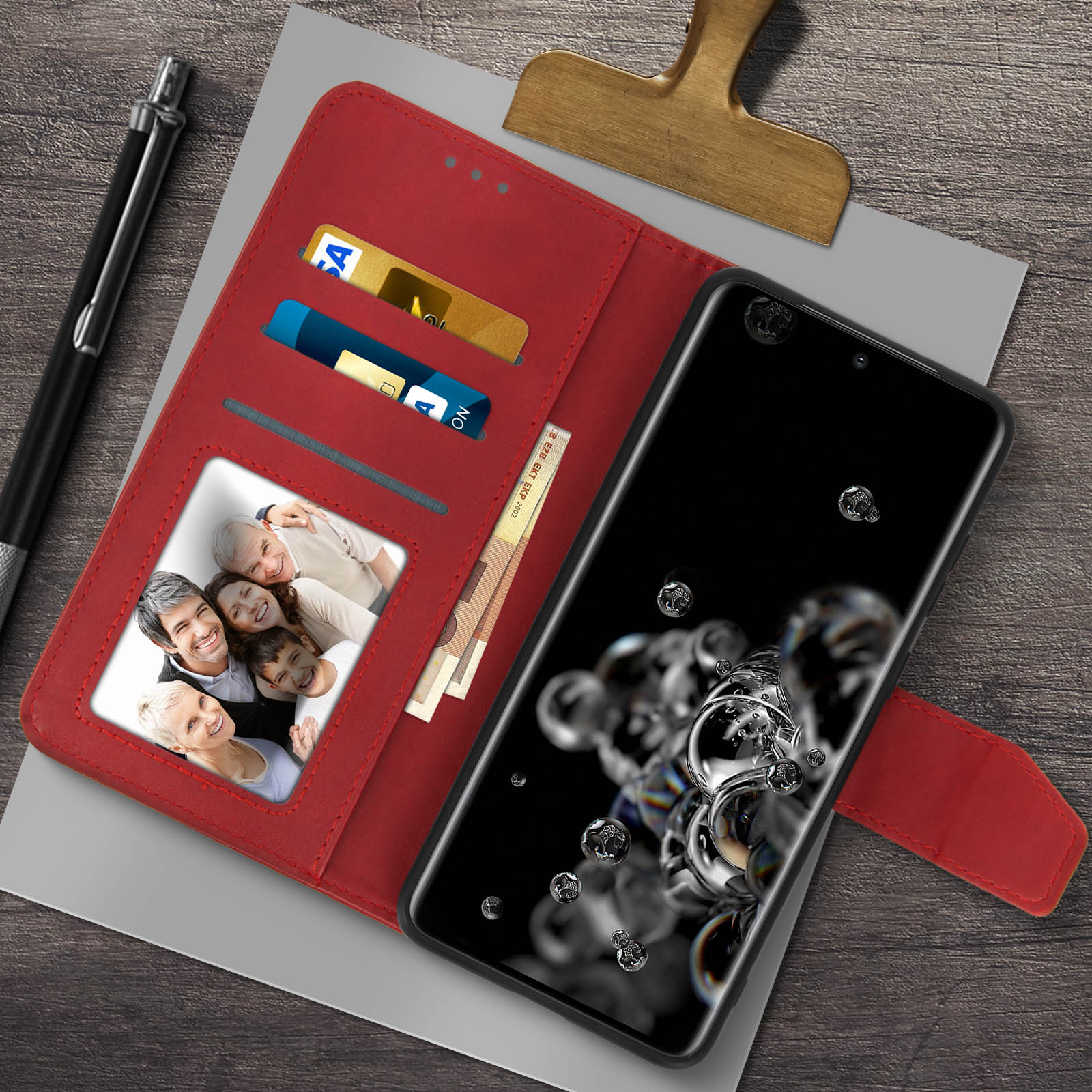 Una custodia rossa con carte e foto di famiglia accanto a uno smartphone nero. Bolle sullo schermo.