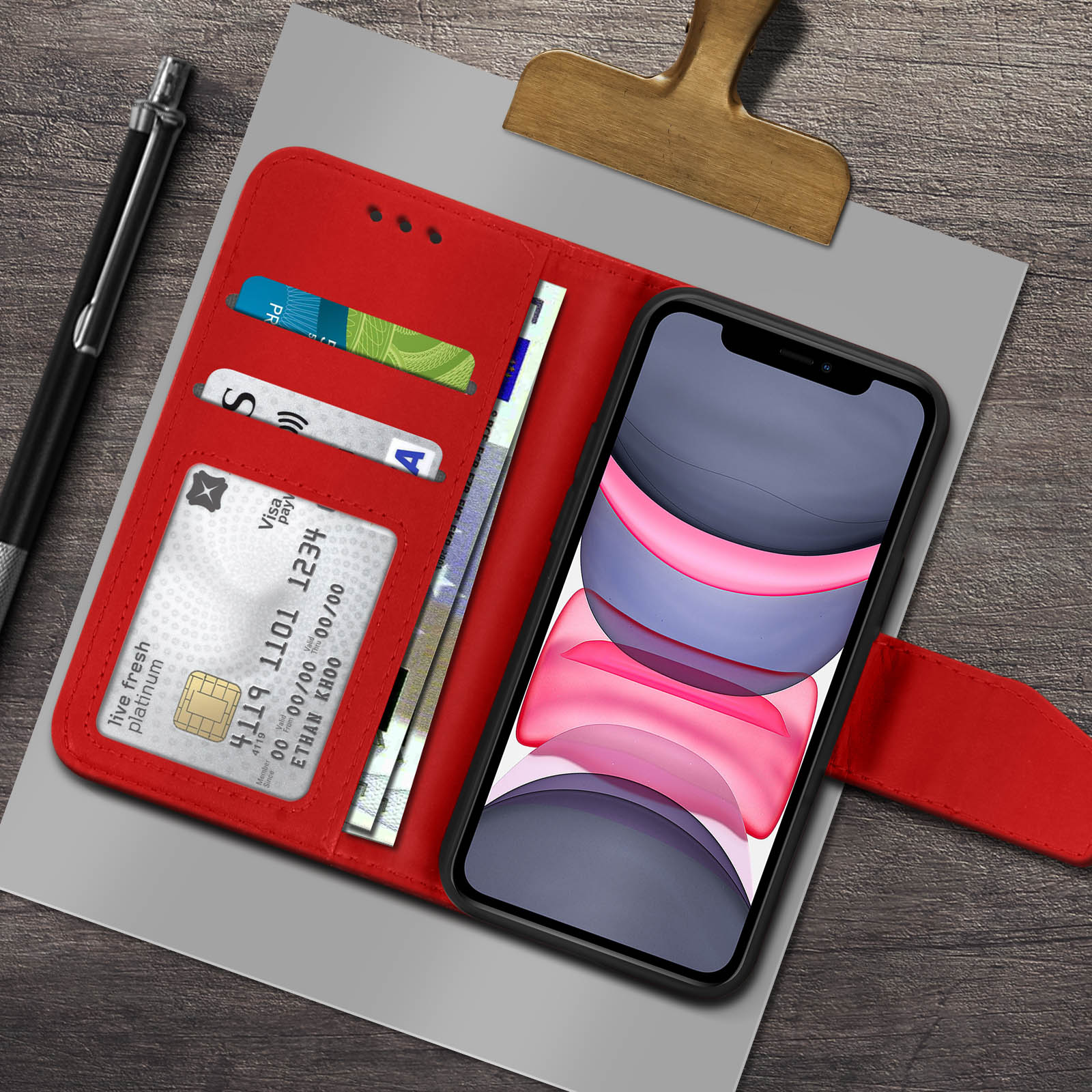 Custodia rossa con carte, telefono con immagine astratta e penna su superficie di legno.