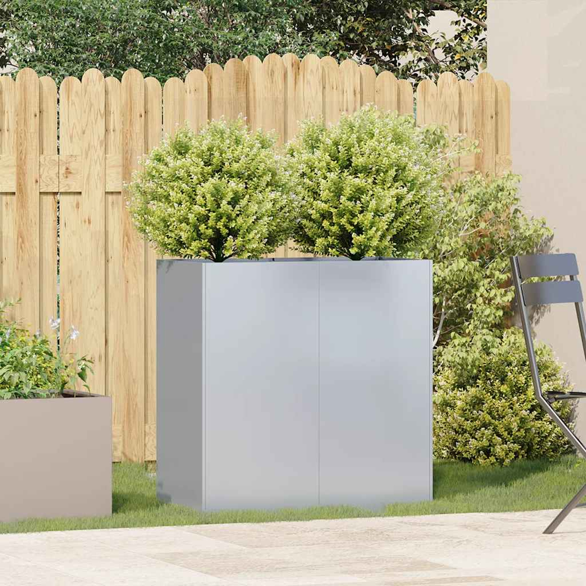 Una scena di giardino moderno con due grandi fioriere con cespugli verdi. Una recinzione di legno e una sedia sono presenti.